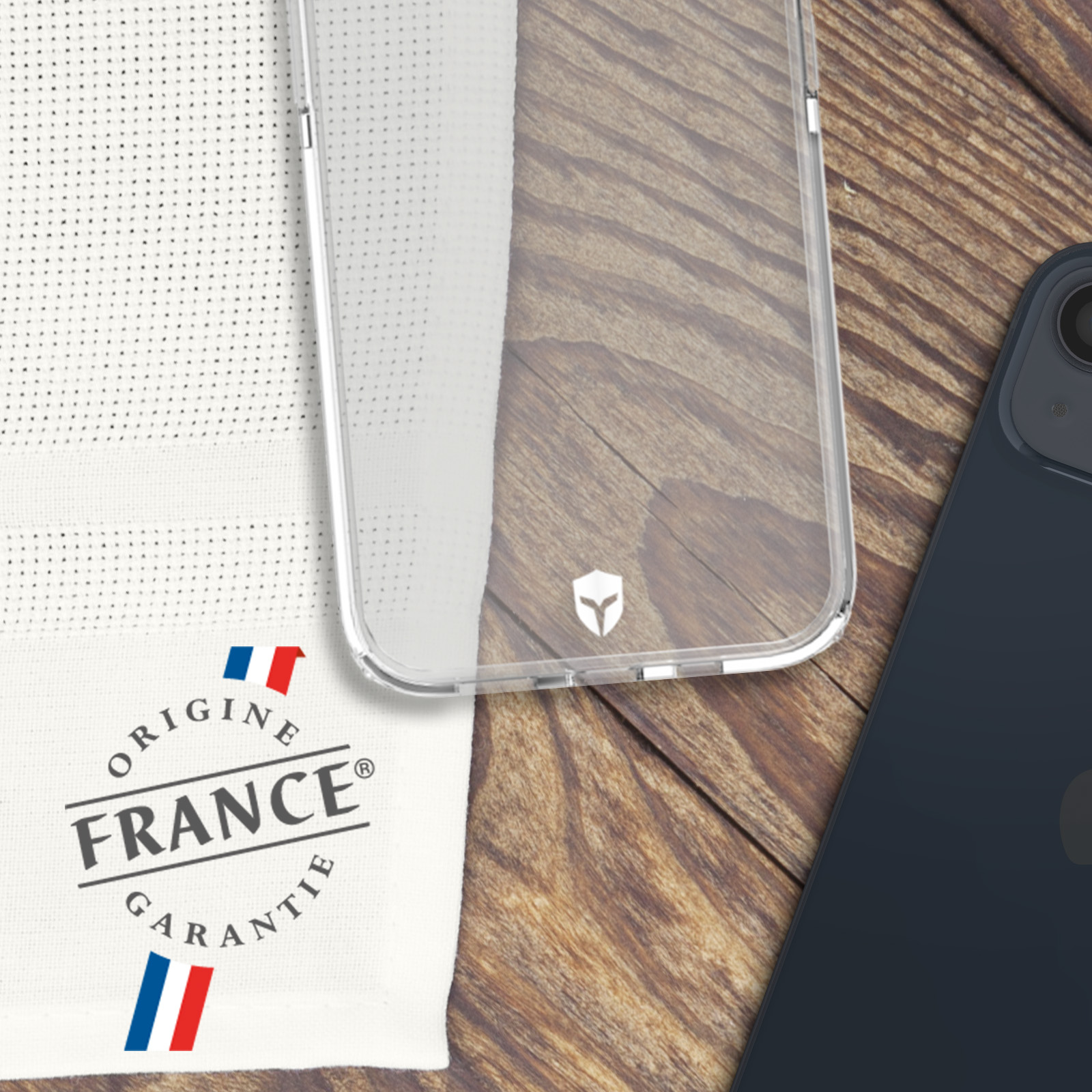 Custodia trasparente, tessuto bianco con logo Francia e telefono blu scuro su legno.