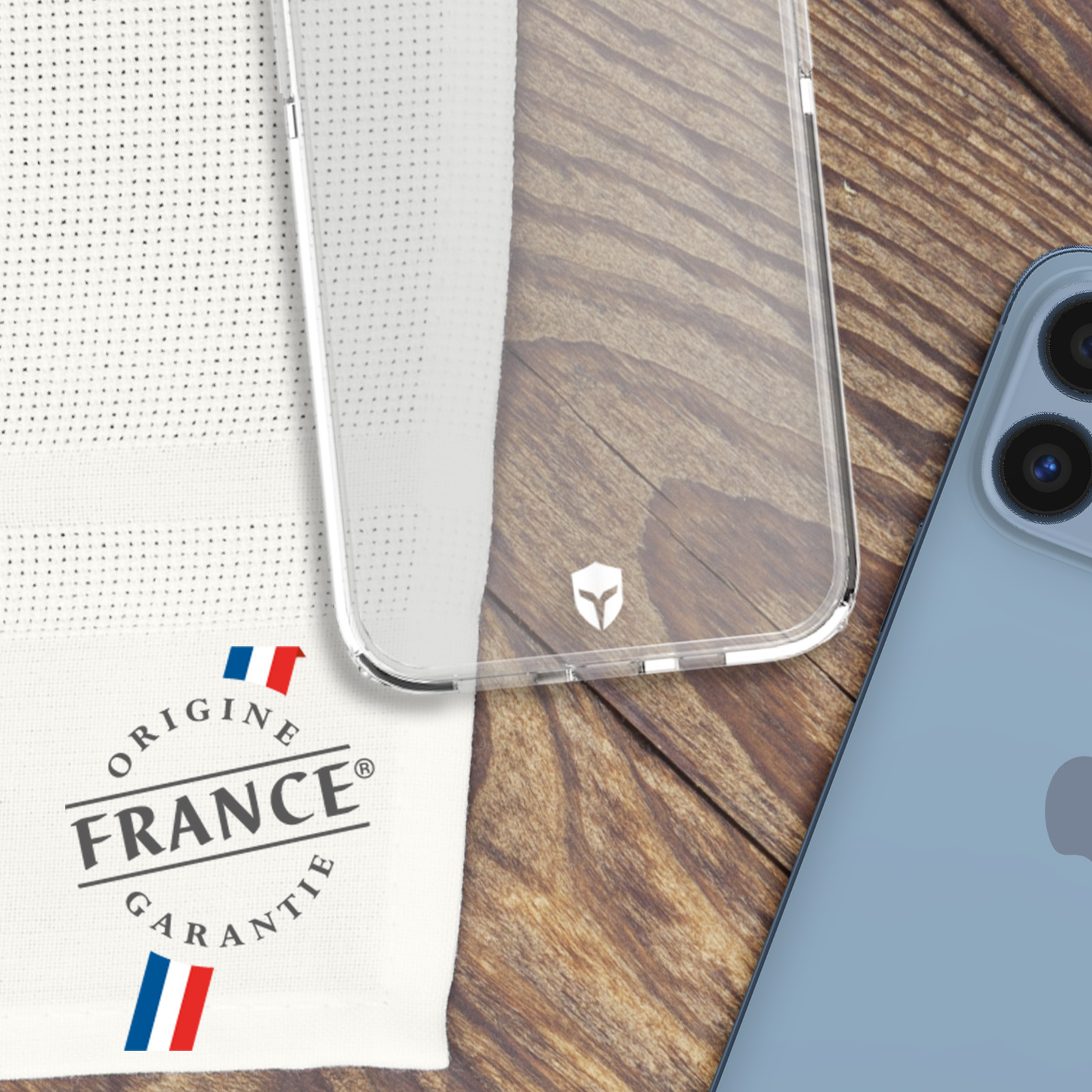 Una custodia trasparente per telefono e un telefono blu. Etichetta di garanzia francese su tessuto bianco.