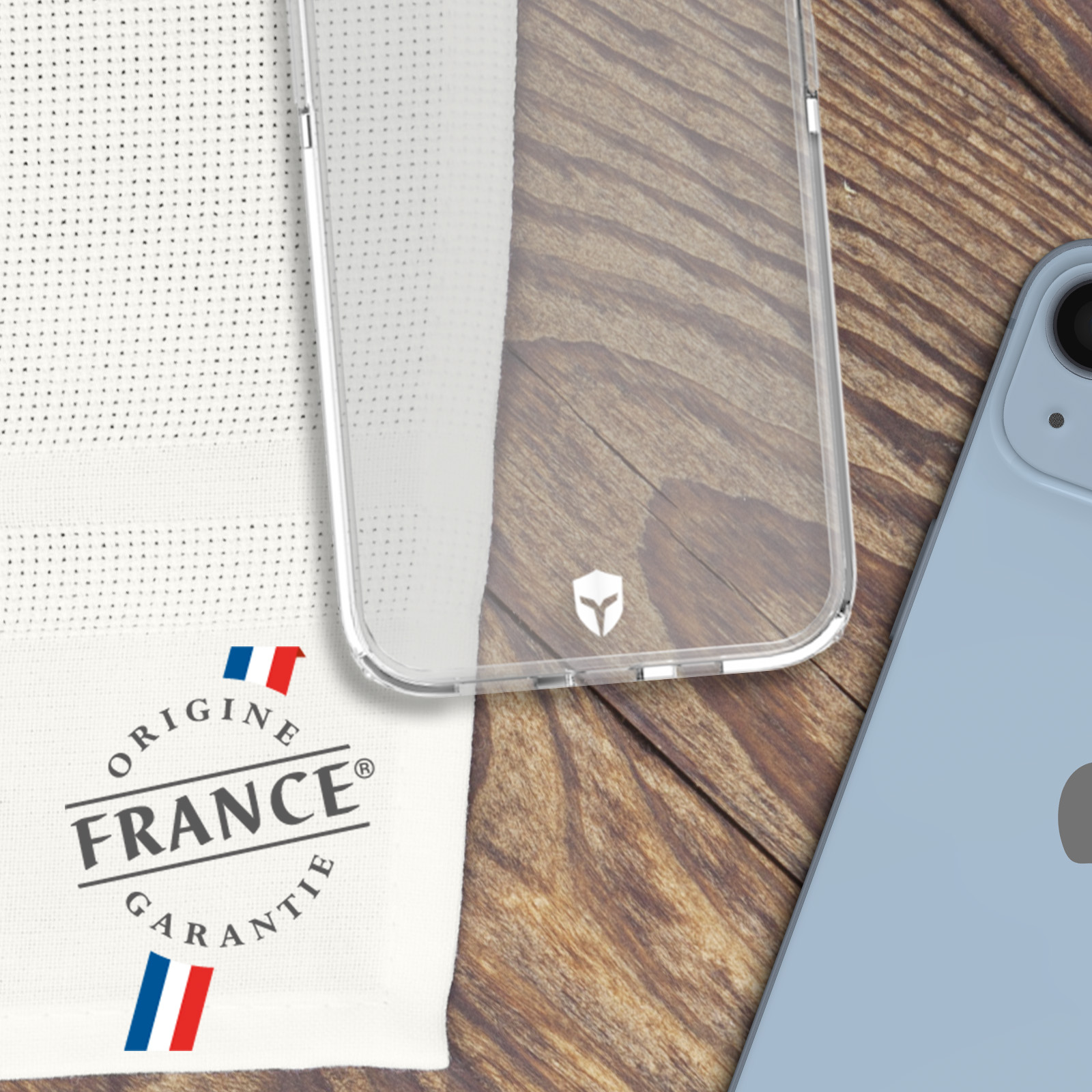 Transparante telefoonhoes met een witte doek en een blauwe telefoon op een houten oppervlak.