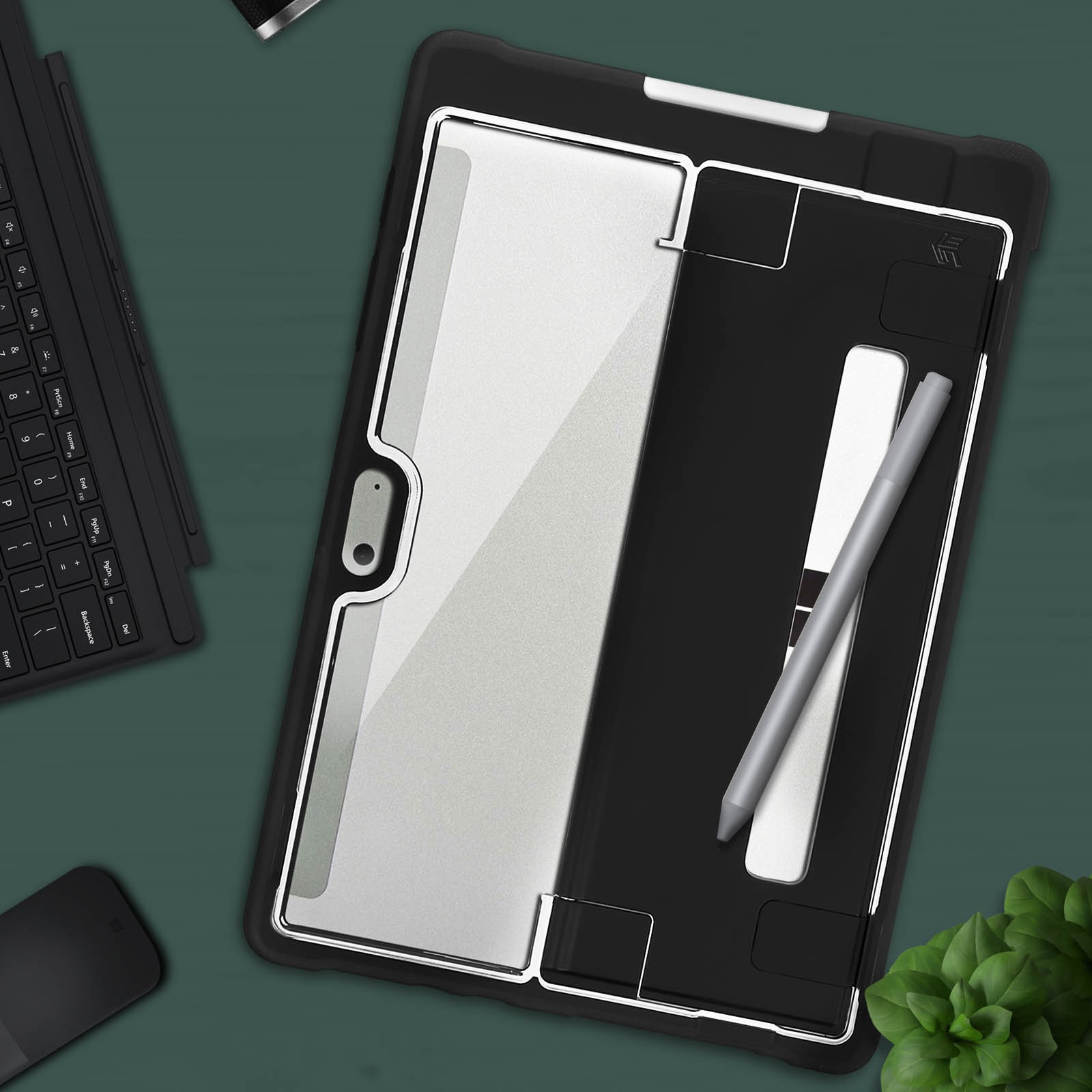 Un tablet in una custodia nera con una penna d'argento su una superficie verde scuro.