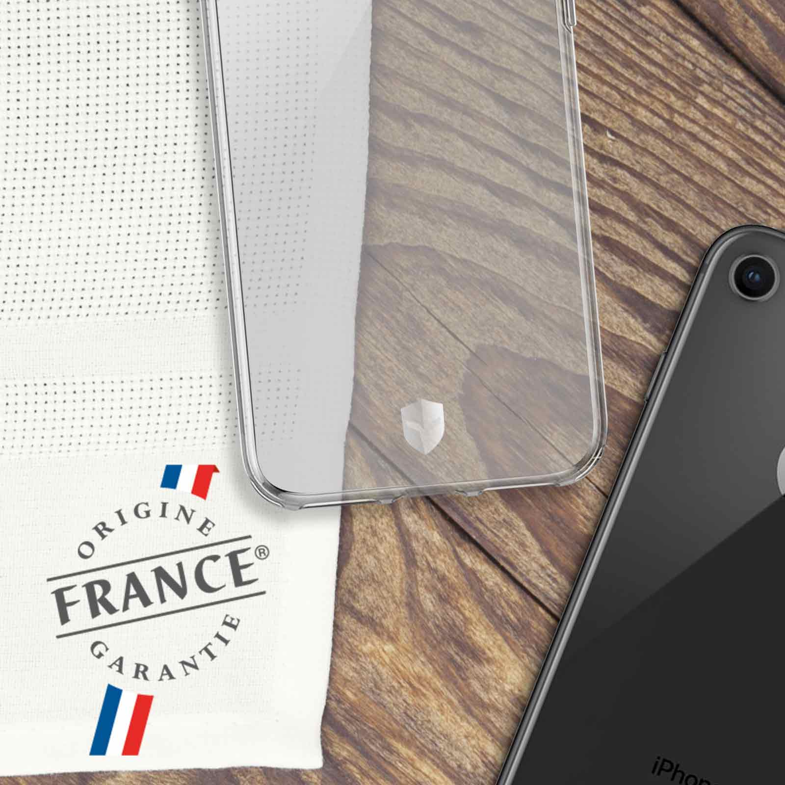 Coque de téléphone transparente, tissu blanc avec texte français et téléphone noir sur bois.