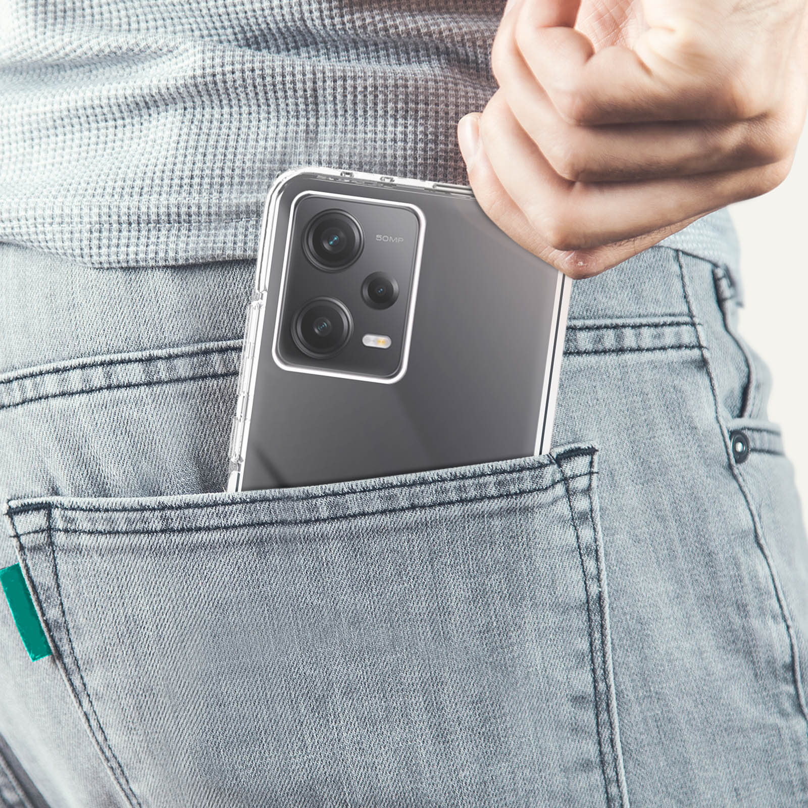 Een telefoon in een doorzichtige hoes in een jeanszak, met de 50MP camera zichtbaar.