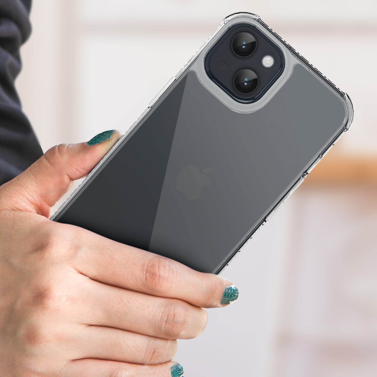Una donna tiene in mano un telefono nero in una custodia trasparente. Le sue unghie sono dipinte di verde.