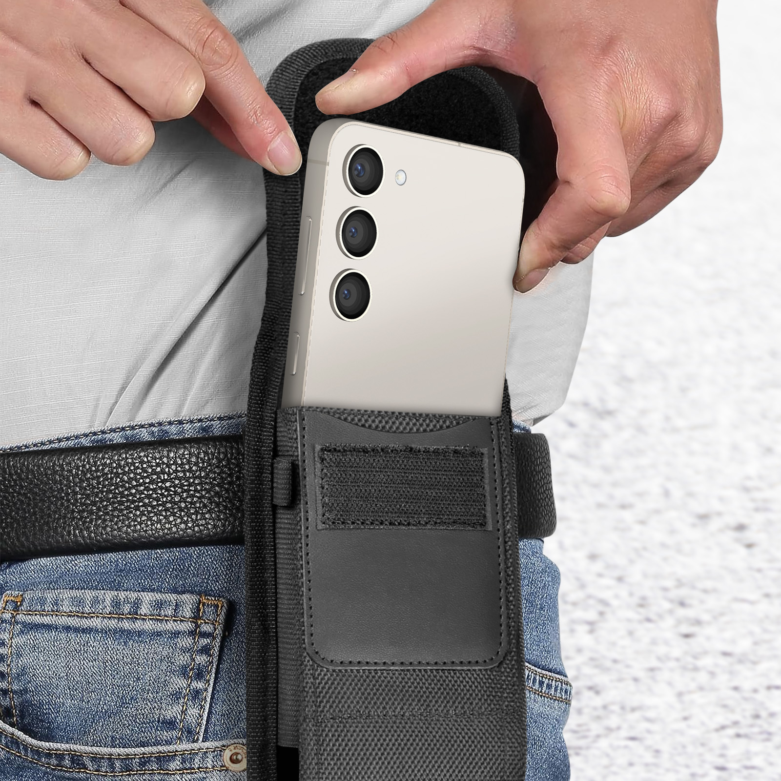 Ein Telefon in einer schwarzen Gürteltasche. Eine Hand legt das Telefon in die Tasche.
