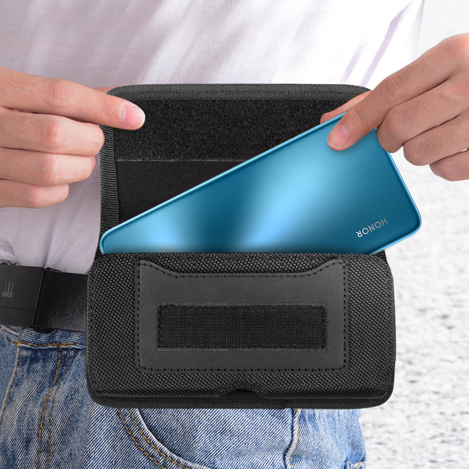 Eine Person legt ein Telefon in eine schwarze Gürteltasche. Jeans-Hintergrund.