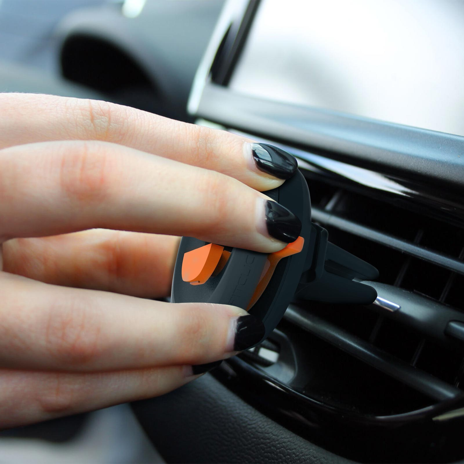 Hand platziert eine schwarz-orangefarbene Telefonhalterung in eine Auto-Luftdüse.
