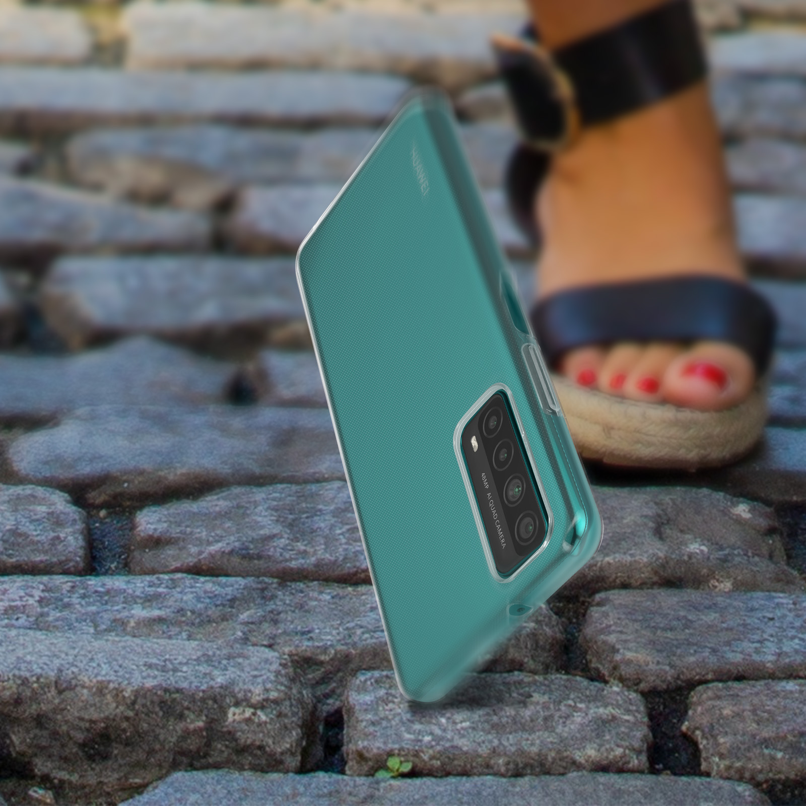 Turkusowe etui na telefon na kamiennej powierzchni, ze stopą w sandałach. Widoczne logo HUAWEI.