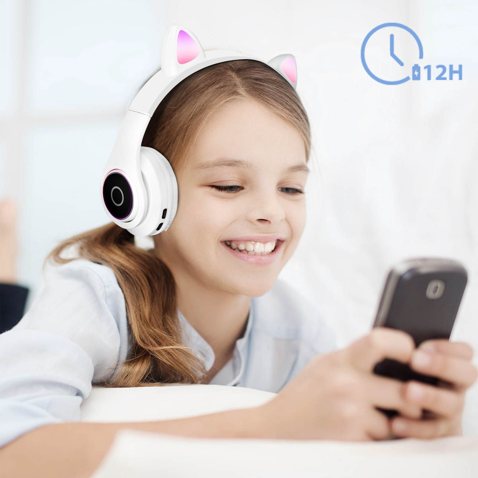 Une fille sourit en portant un casque blanc à oreilles de chat et en tenant un téléphone noir.