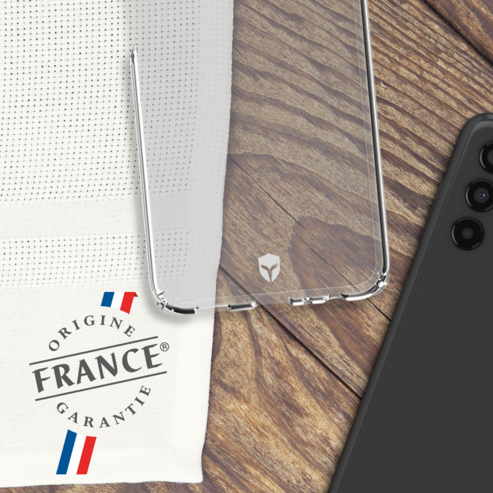 Une coque de téléphone transparente avec un drapeau français et du texte. Un téléphone noir est derrière.