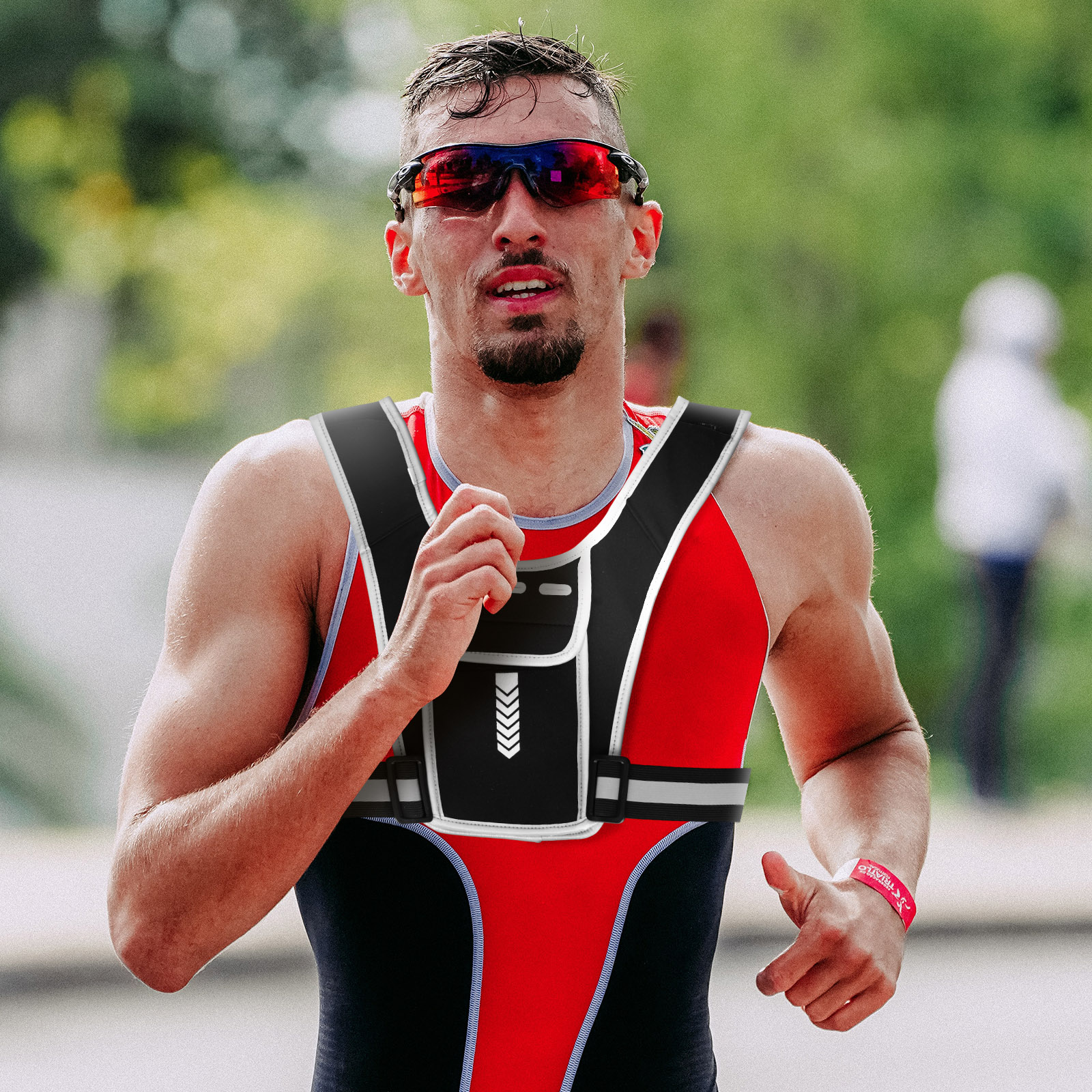 Corridore in gilet, occhiali da sole rossi e braccialetto rosso.