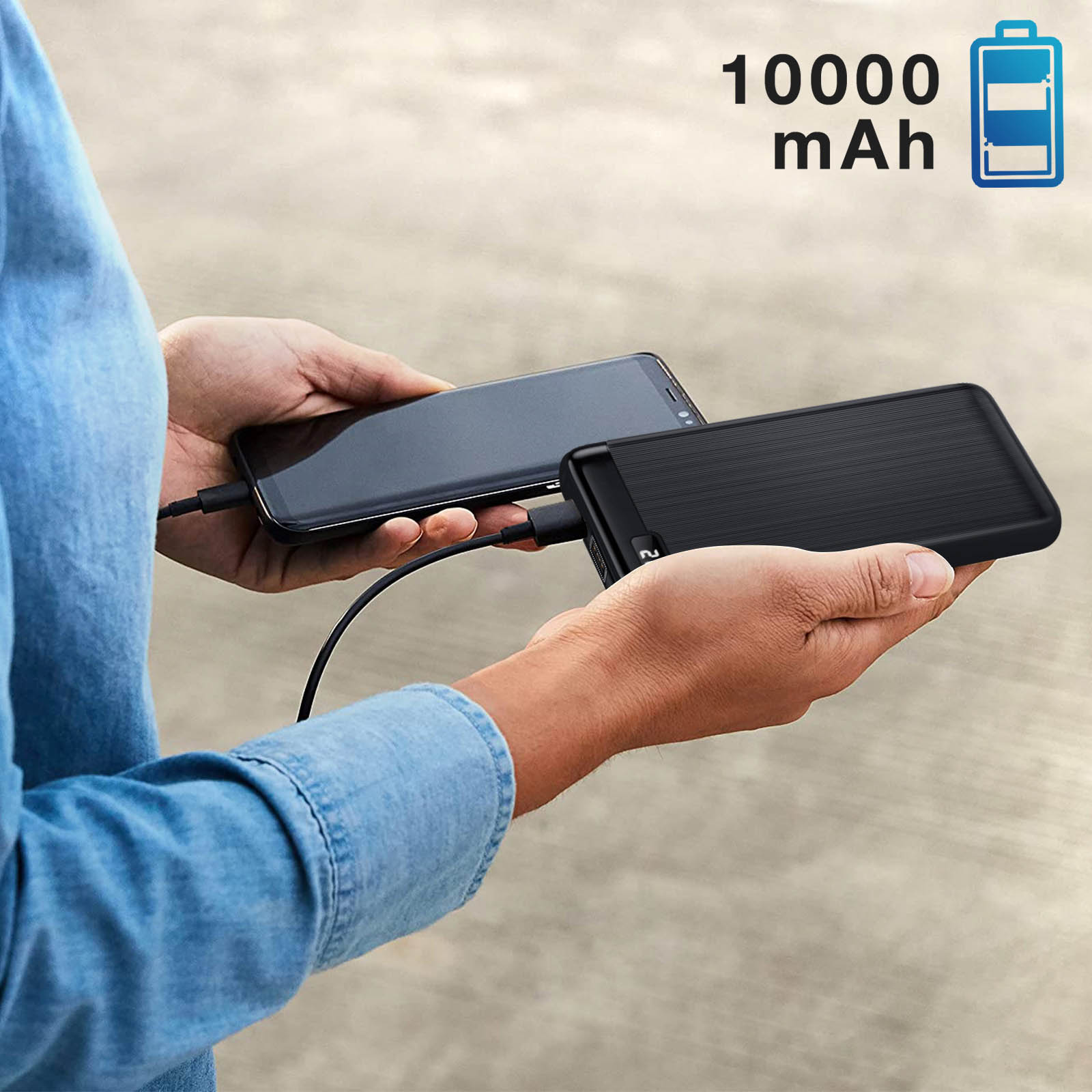 Person hält ein Telefon und eine schwarze Powerbank. Die Powerbank zeigt 10000 mAh.