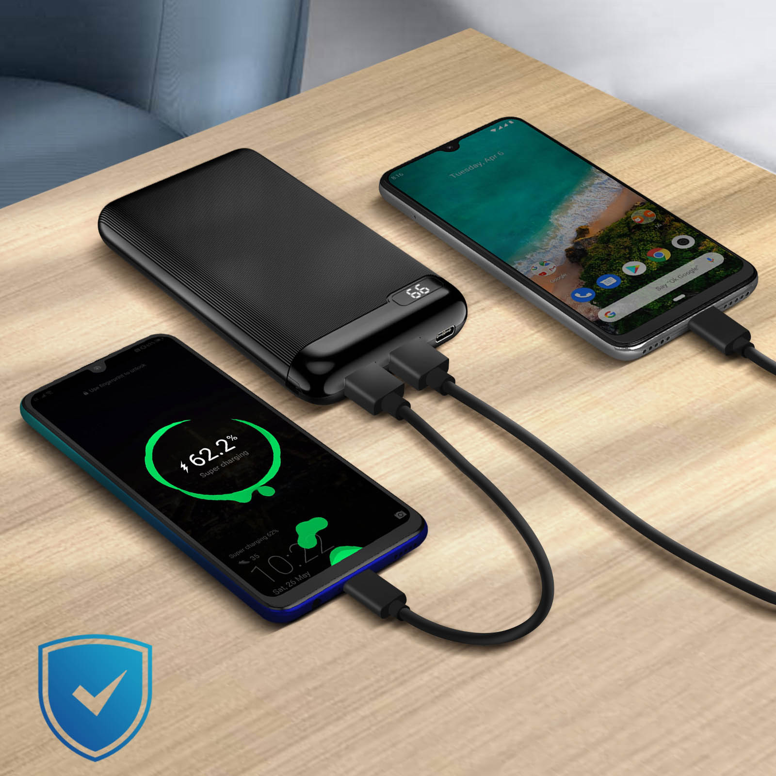 Drei Telefone laden von einer Powerbank auf einem Holztisch.