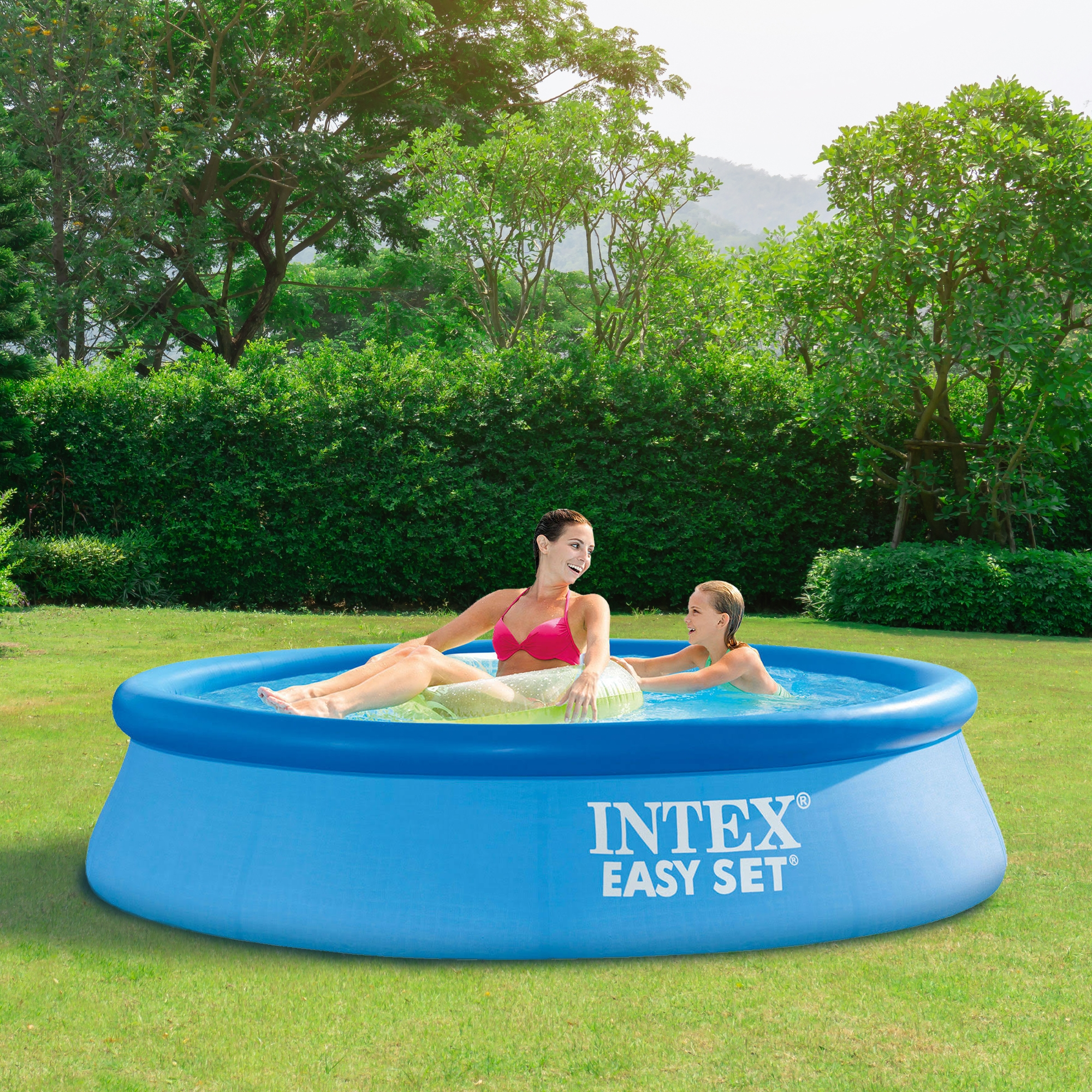 Zwei Frauen in einem blauen Pool. Eine in einem rosa Oberteil, die andere mit einem grünen Aufblasbaren.