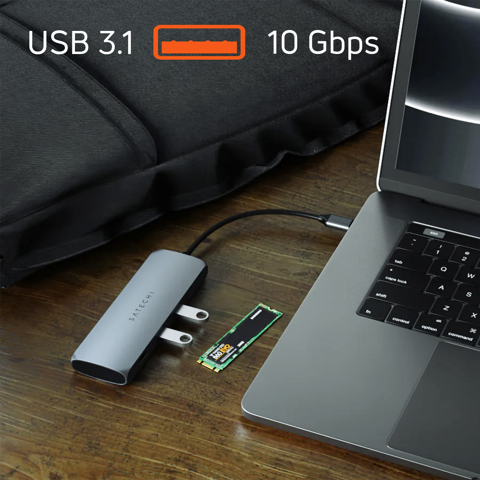 Concentrador USB plateado con unidades USB y portátil en un escritorio.