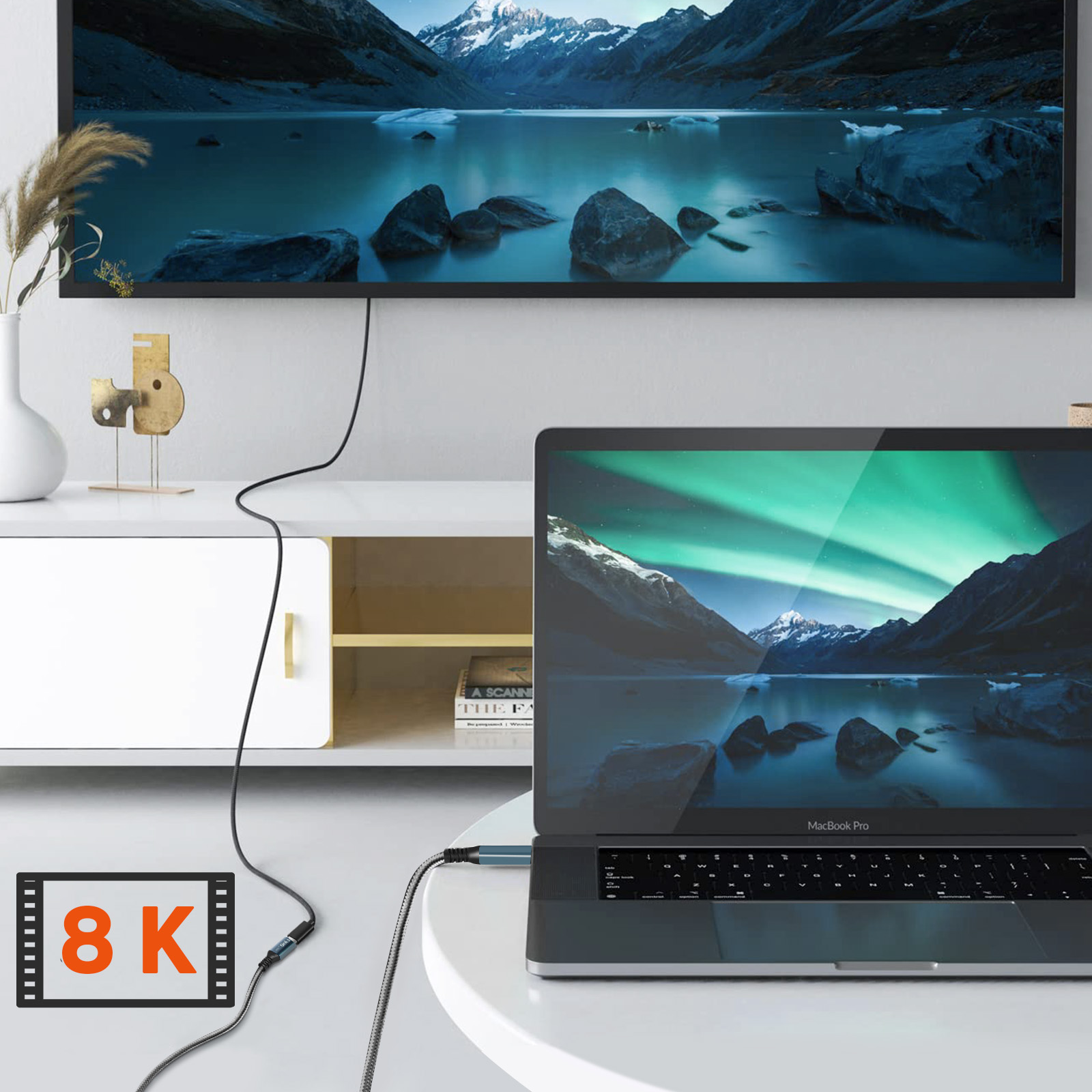 Laptop e TV mostrano una scena di lago di montagna, collegati tramite cavo.