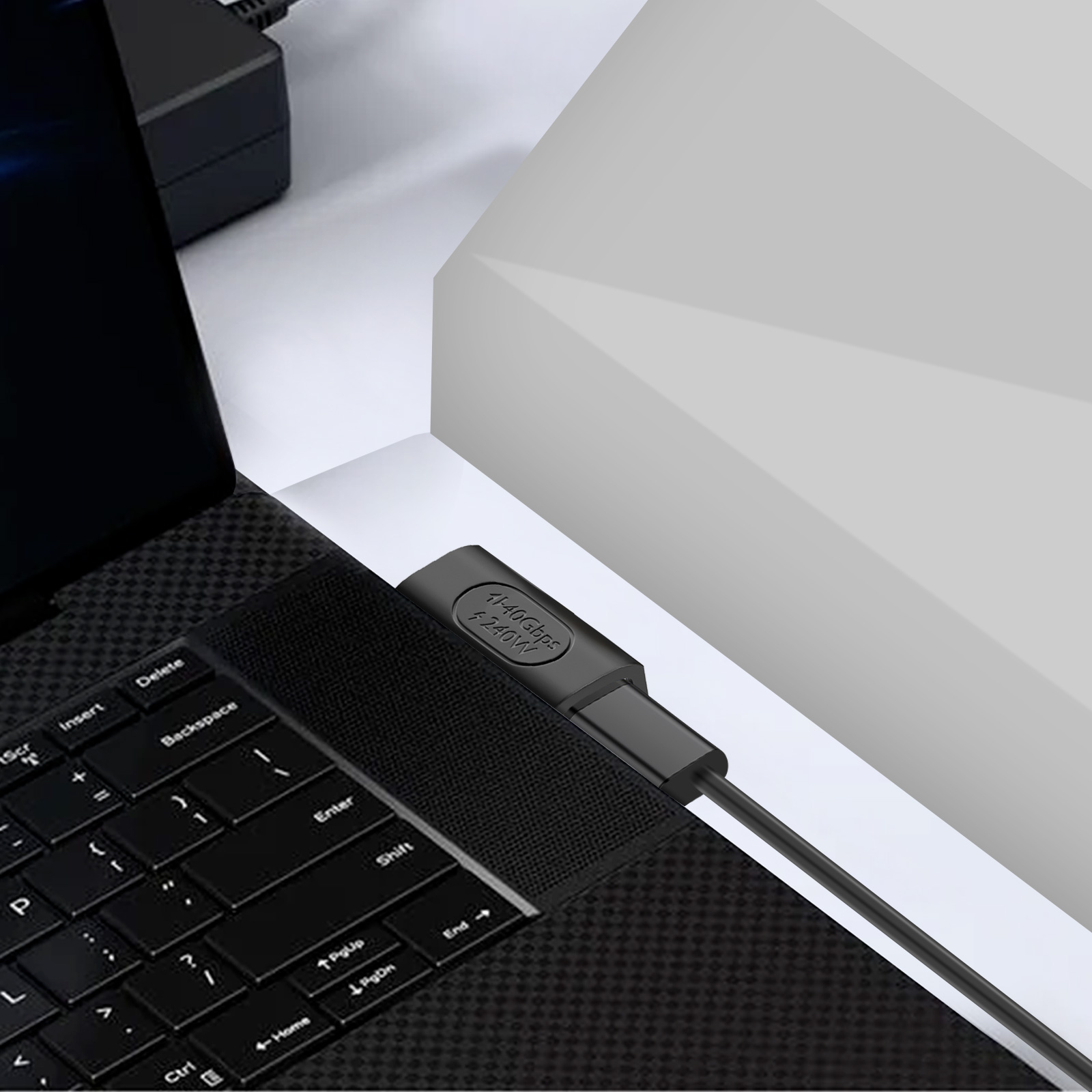 Un cavo USB-C nero collegato a un laptop e una parete bianca. Il cavo ha stampato 40 Gbps.