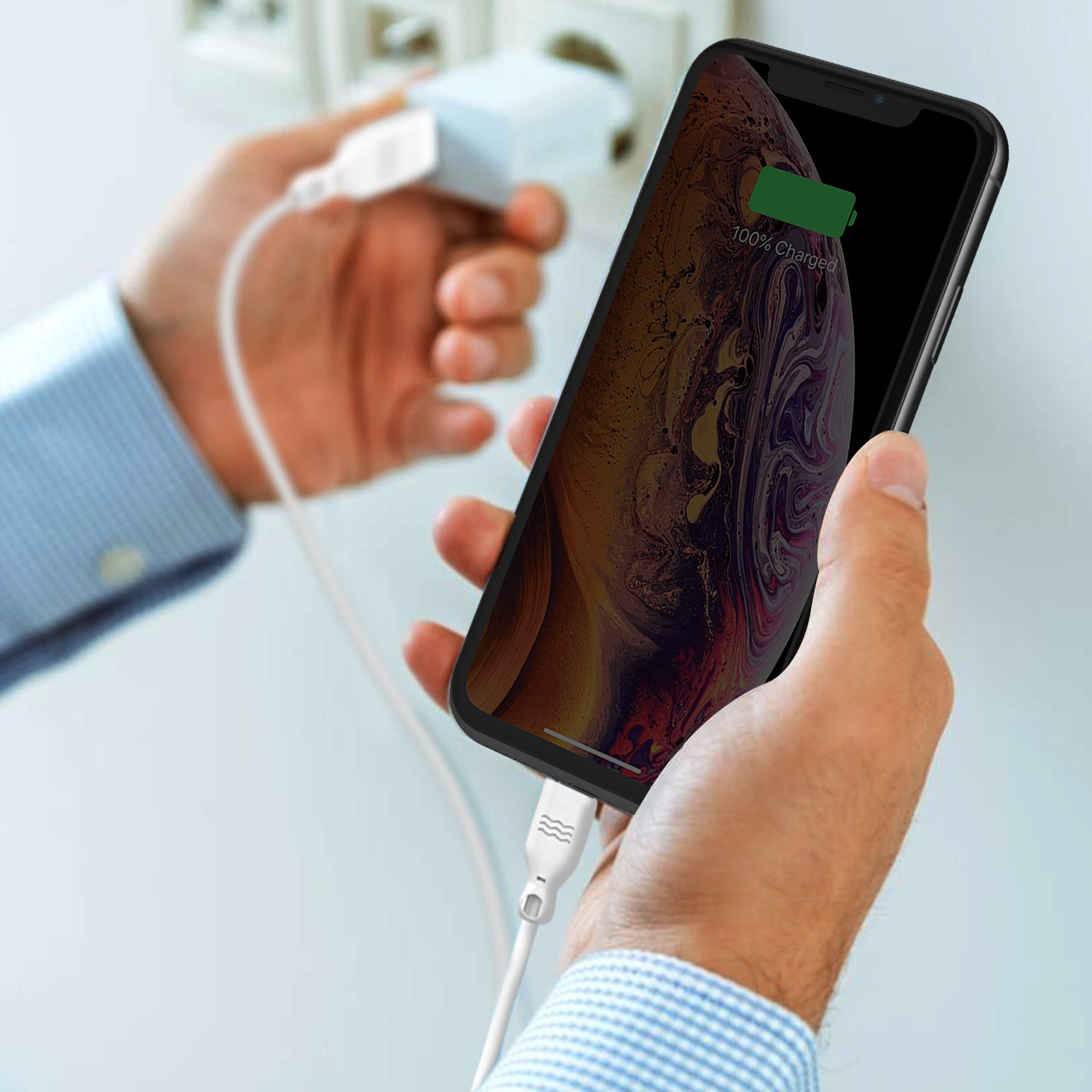 Hände halten ein Telefon, das geladen wird, mit 100% geladen. Weißes Kabel angeschlossen.