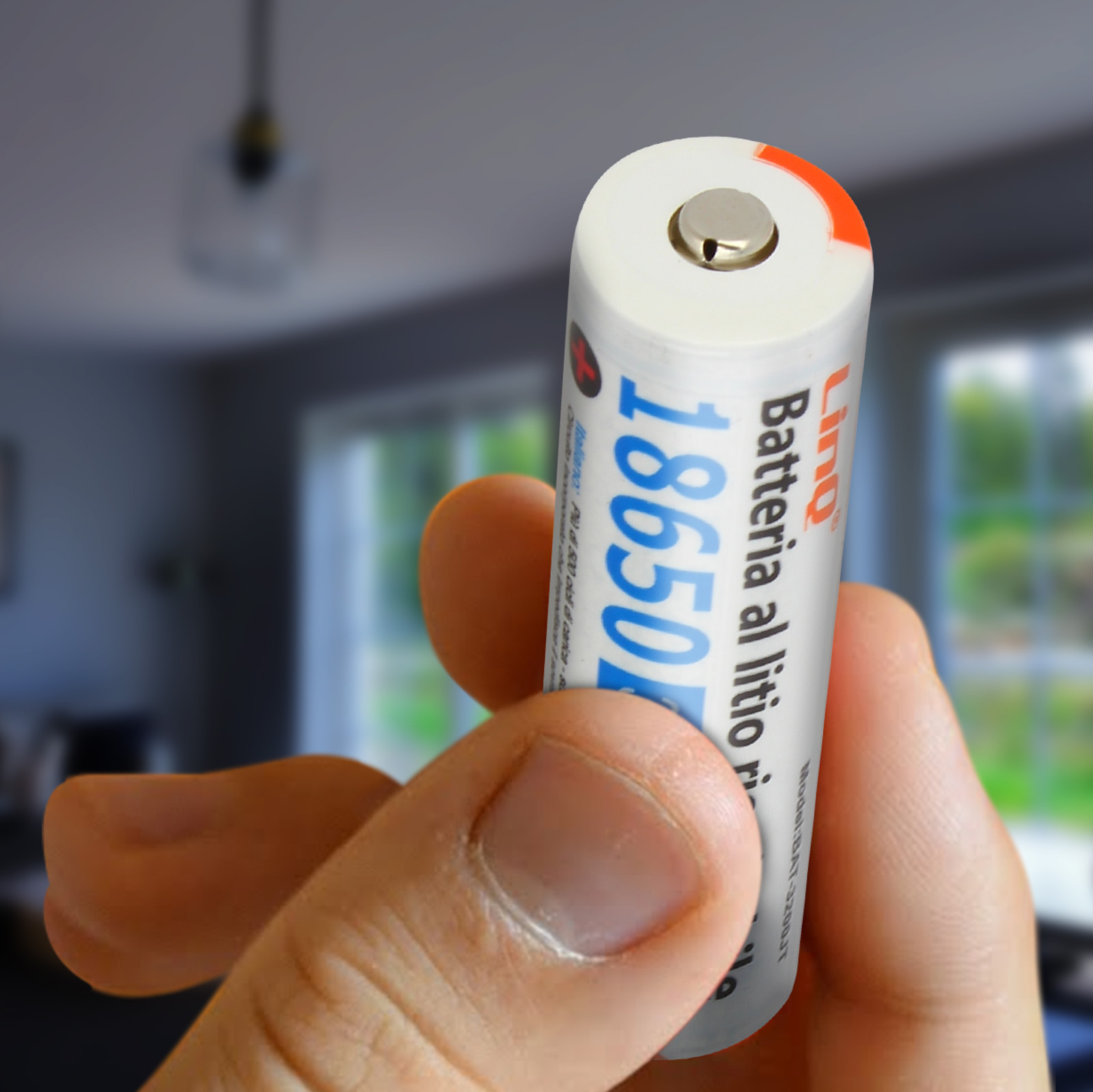 Main tenant une batterie Li-ion 18650 blanche et bleue, avec un arrière-plan flou.