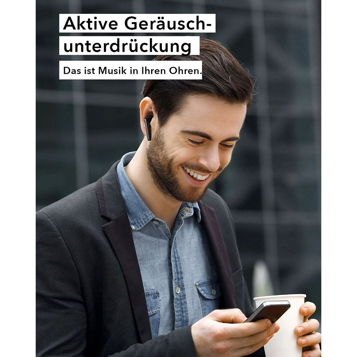 Mann mit Ohrhörern, lächelnd, hält ein Telefon und eine Tasse. Text: Aktive Geräuschunterdrückung.