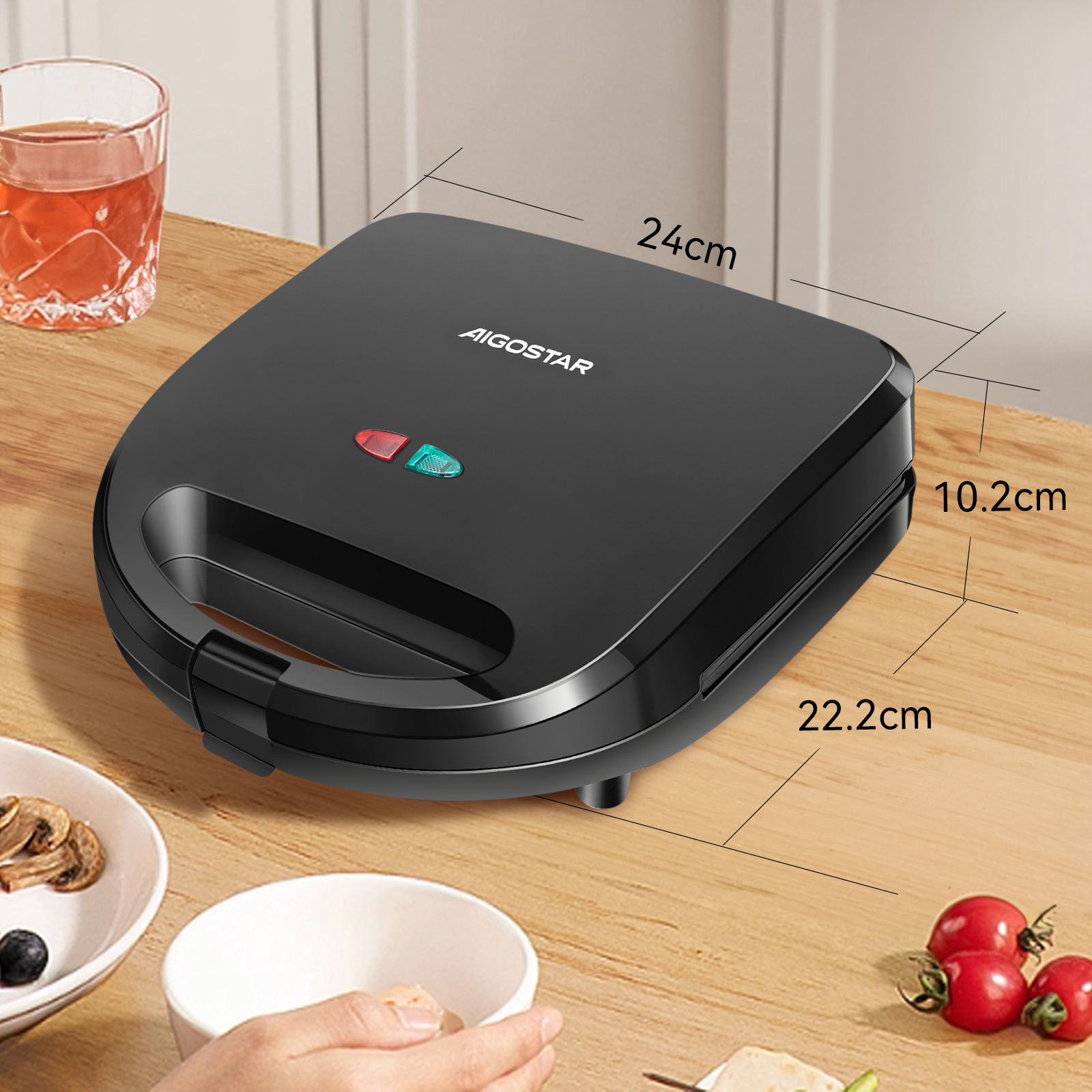 Una sandwichera AIGOSTAR negra sobre una mesa de madera, con medidas y alimentos cerca.