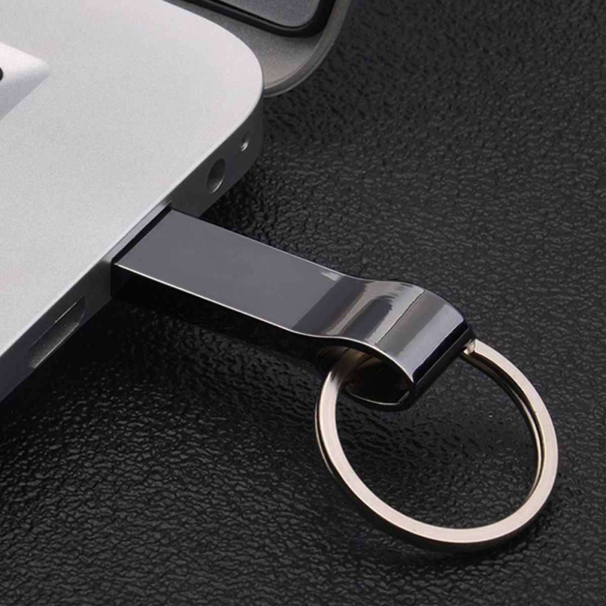 Ein USB-Stick, der in einen Laptop eingesteckt ist, mit einem Schlüsselring befestigt.