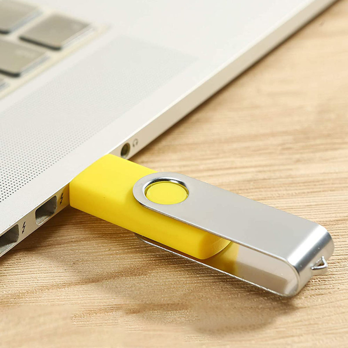 Gelber USB-Stick in einen Laptop gesteckt, mit silbernem Metallgehäuse.