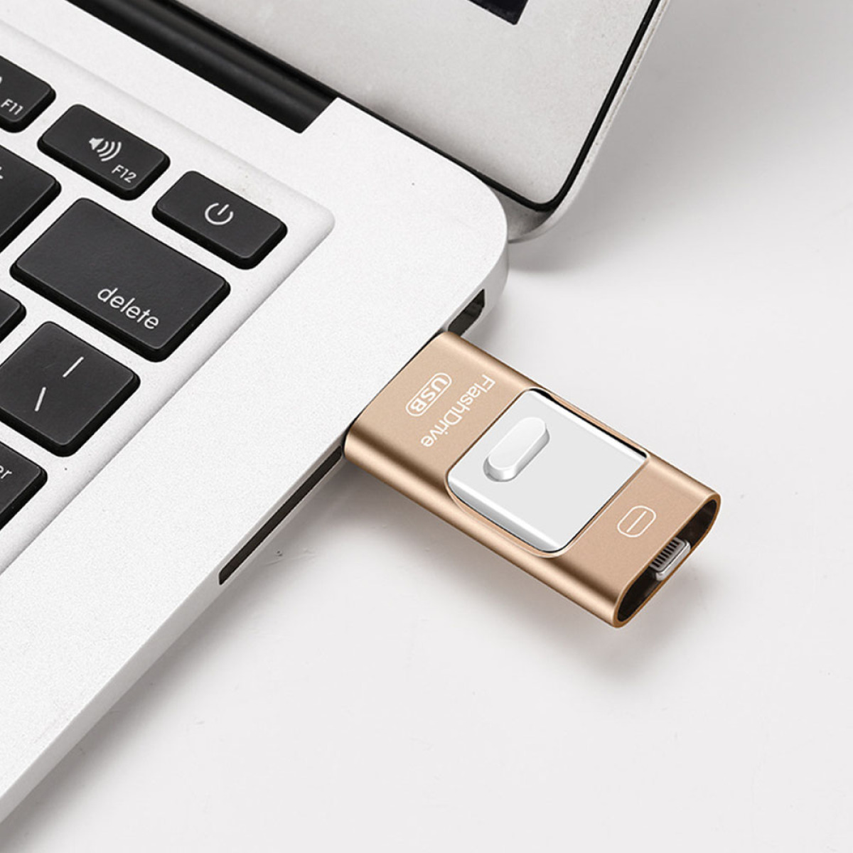 Ein goldener USB-Stick, der in einen silbernen Laptop gesteckt ist, mit sichtbarer Löschtaste.