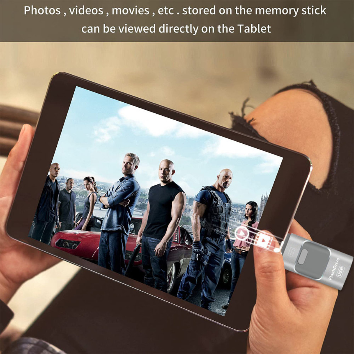Tablet mit Filmszene, gehalten von Händen, mit angeschlossenem USB-Stick.