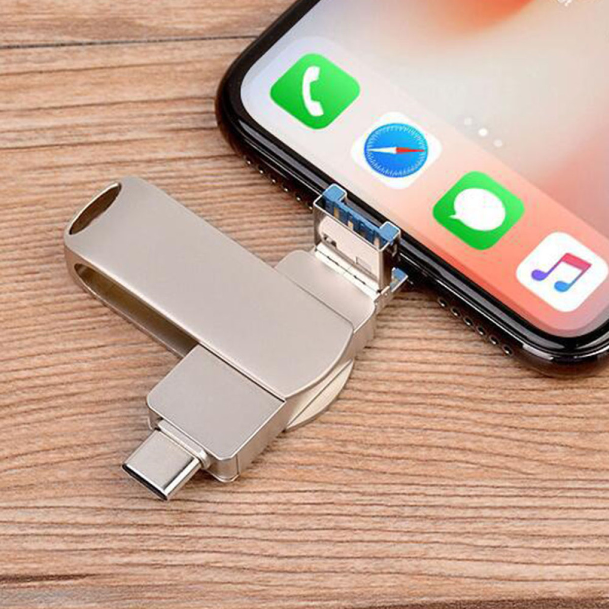 Silberner USB-Stick, der mit einem Mobiltelefon verbunden ist, auf Holzoberfläche.