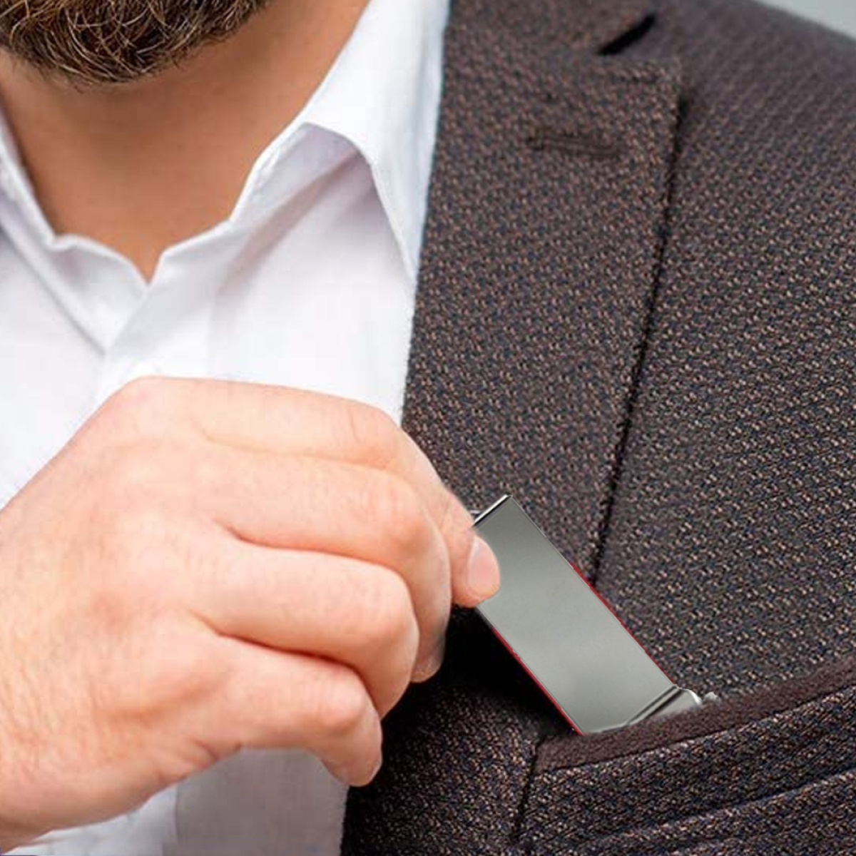 Mann im Anzug holt einen silbernen USB-Stick aus der Tasche. Der Stick hat einen roten Streifen.