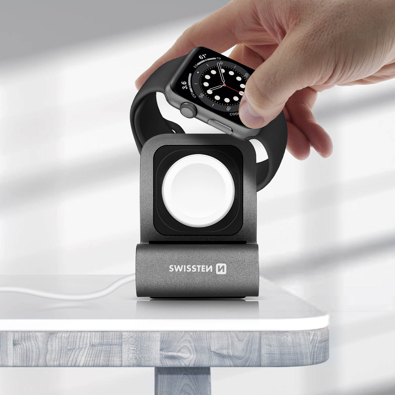 Eine Hand, die eine Apple Watch auf eine Ladestation legt. Der Ständer hat das SWISSEN-Logo.