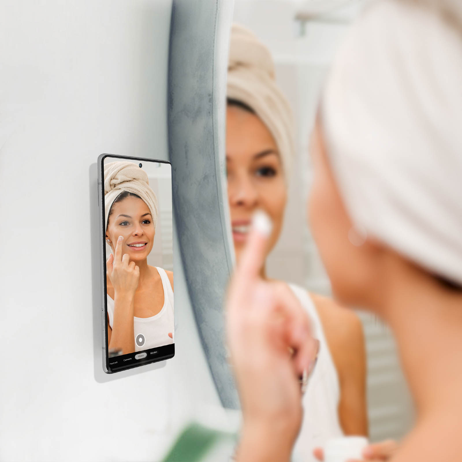 Donna con asciugamano in testa applica crema viso guardandosi allo specchio.
