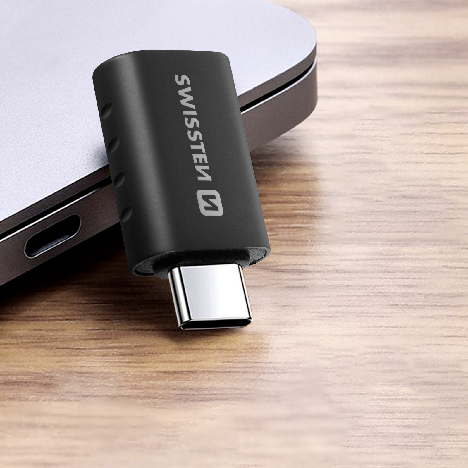 Ein schwarzer USB-C-Adapter, der an einen Laptop angeschlossen ist. Der Adapter hat das Wort SWISSTEN.