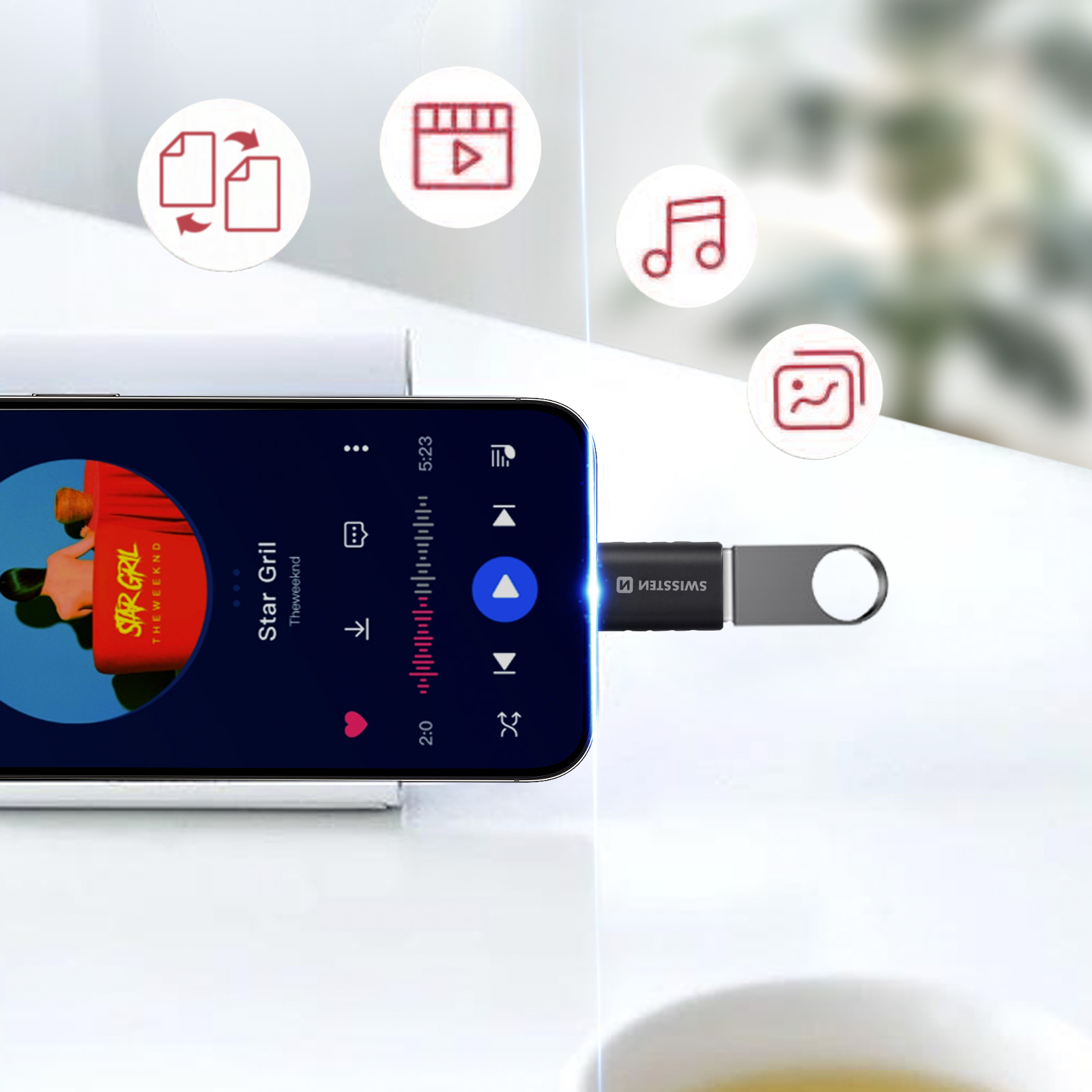Un téléphone affiche de la musique. Une clé USB est connectée. Icônes et une tasse en arrière-plan.