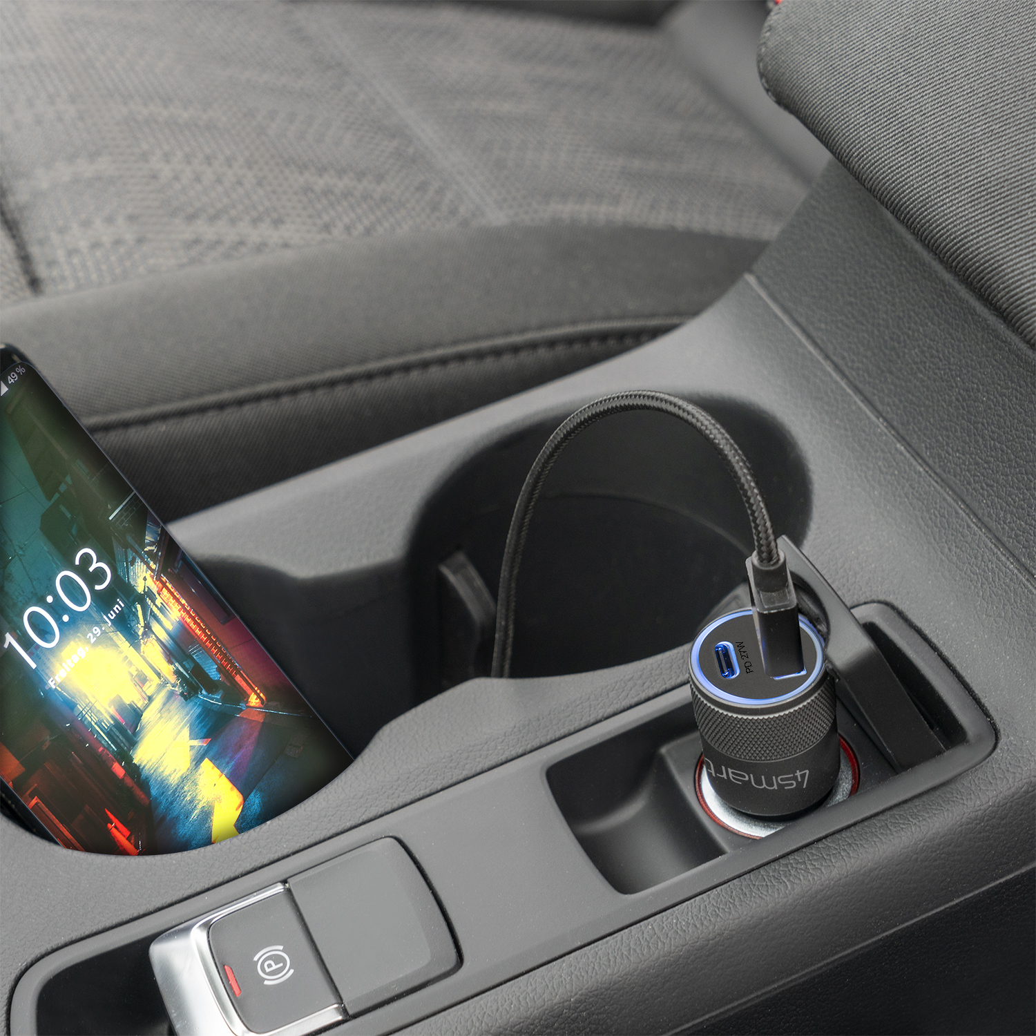 Becherhalter im Auto mit Telefon und Kabel, das in ein Autoladegerät eingesteckt ist. Telefon zeigt 10:03.