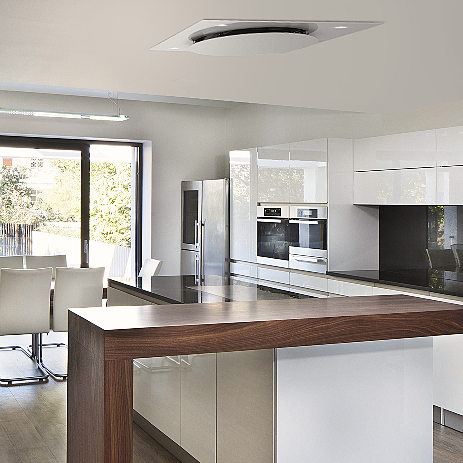 Cucina moderna con mobili bianchi, piano scuro e isola in legno. Grandi finestre e un ventilatore a soffitto sono visibili.
