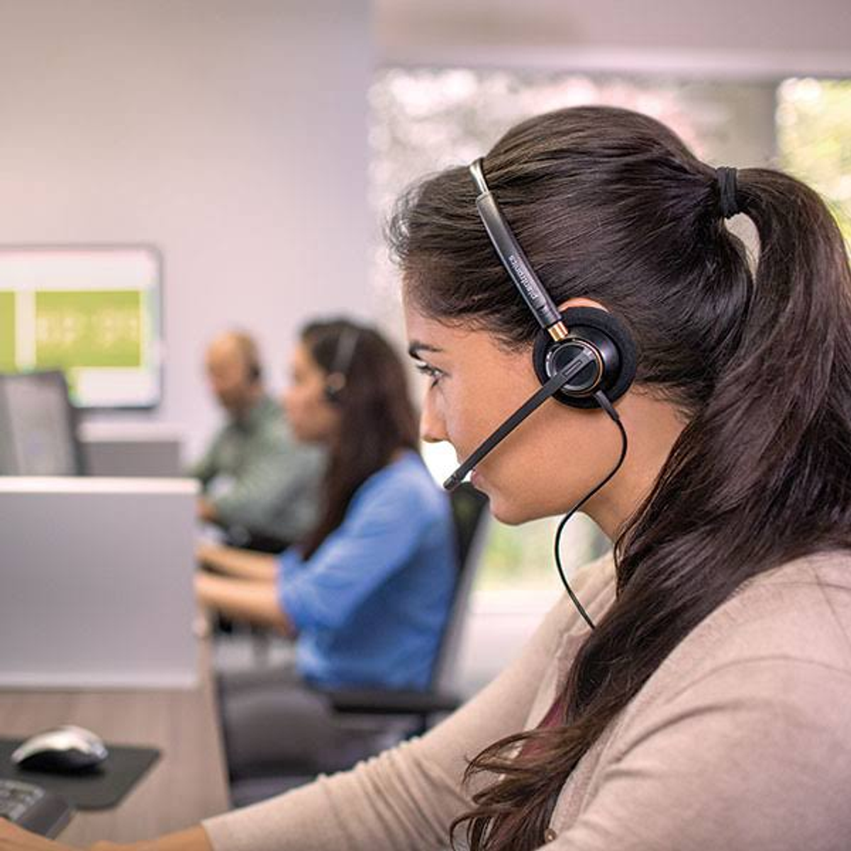 Mujer con auriculares, en un escritorio, en un centro de llamadas.