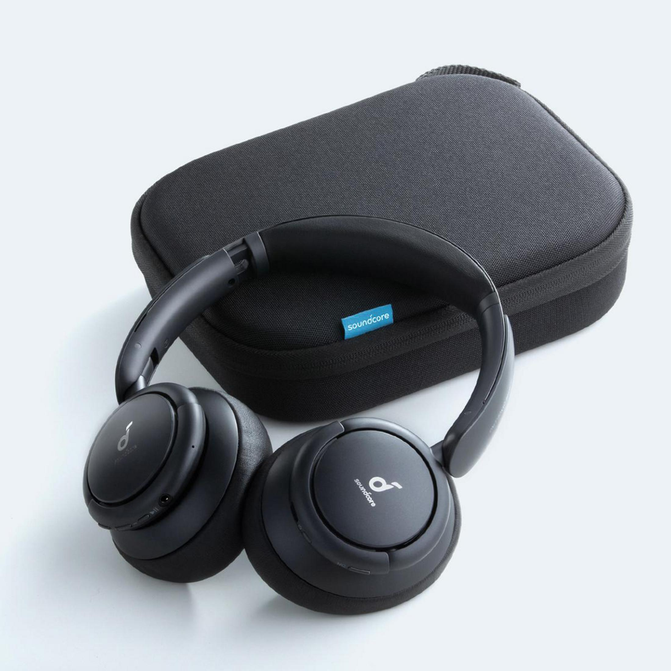 Auriculares y estuche negros sobre una superficie blanca. Los auriculares tienen el logotipo de Soundcore.