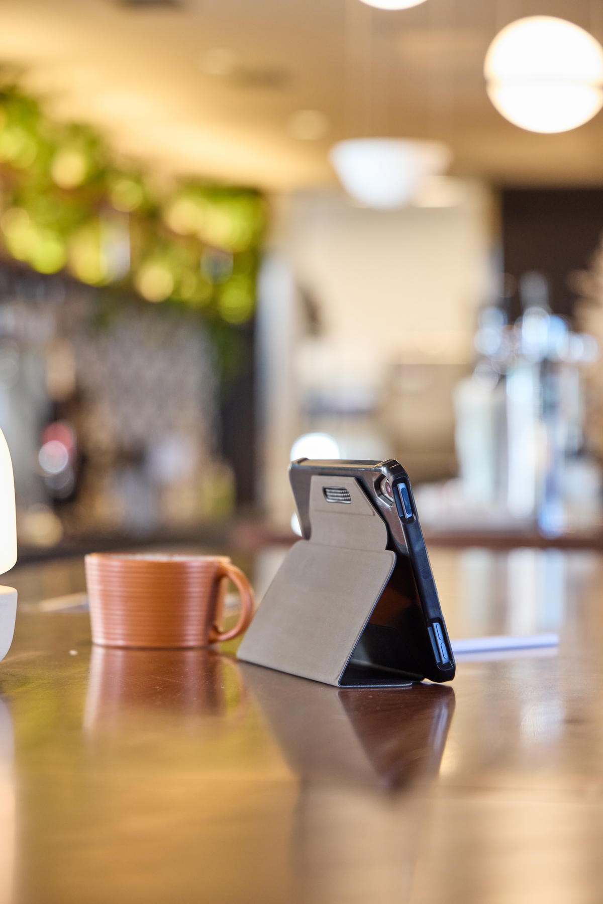 Ein Telefon in einer Hülle, auf einer Theke neben einer Kaffeetasse in einem Café aufgestellt.