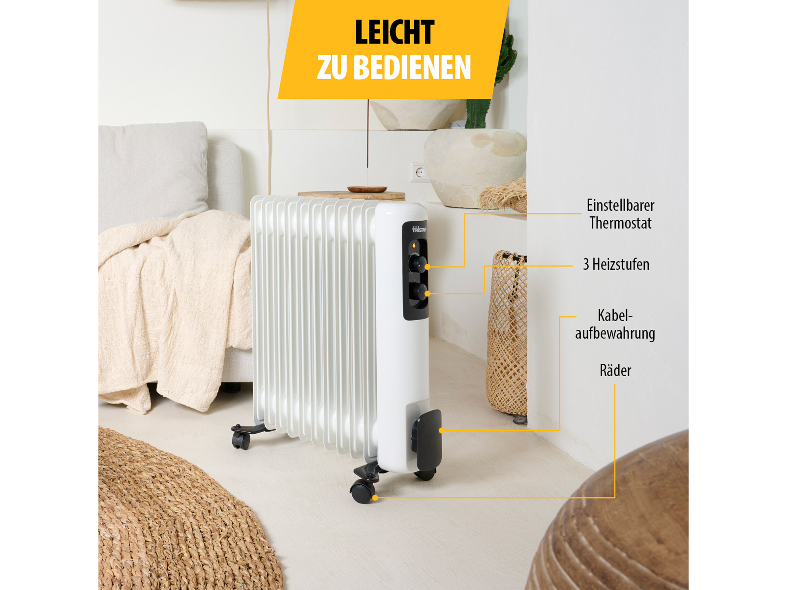 Biały grzejnik olejowy na kółkach, w pobliżu ściany z niemieckim tekstem. Zawiera etykiety ustawień i funkcji.