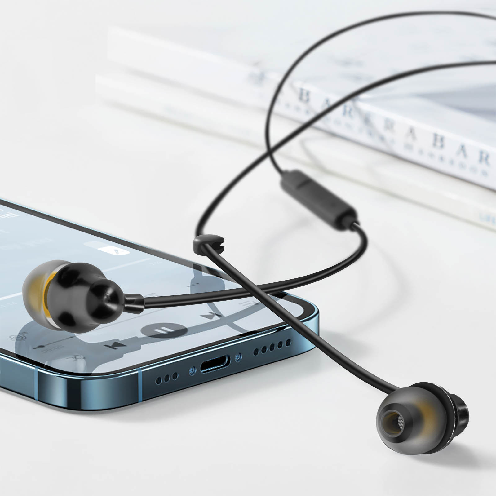 Auricolari neri con punte gialle collegati a uno smartphone blu su una superficie bianca.
