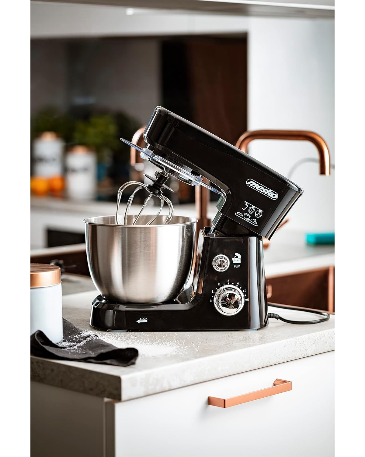 Schwarzer Küchenmixer auf einer Arbeitsplatte. Silberne Schüssel, Schneebesenaufsatz.