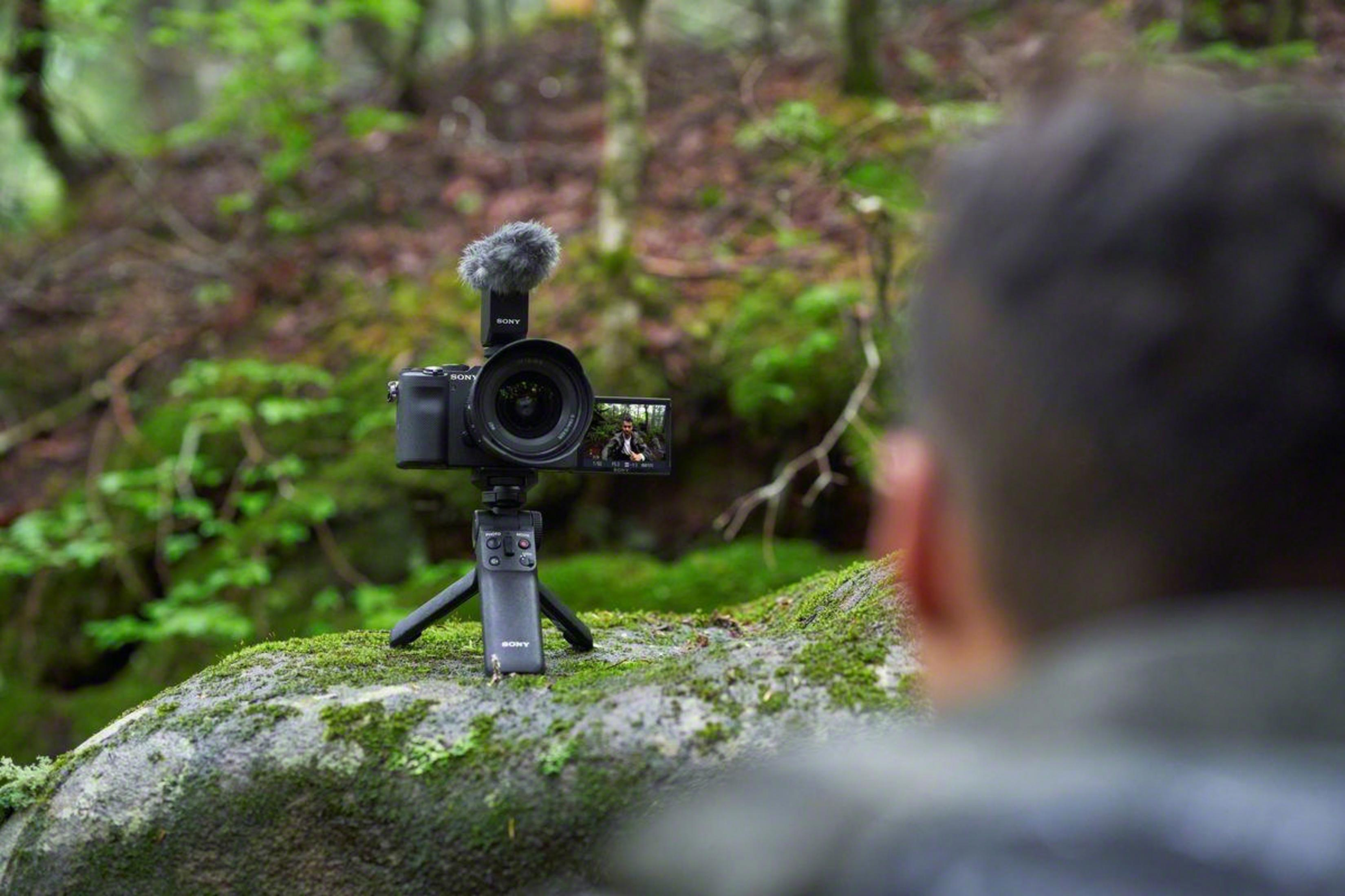 Een persoon die filmt met een camera op een statief in een bos. De camera is gericht op een bosscène.