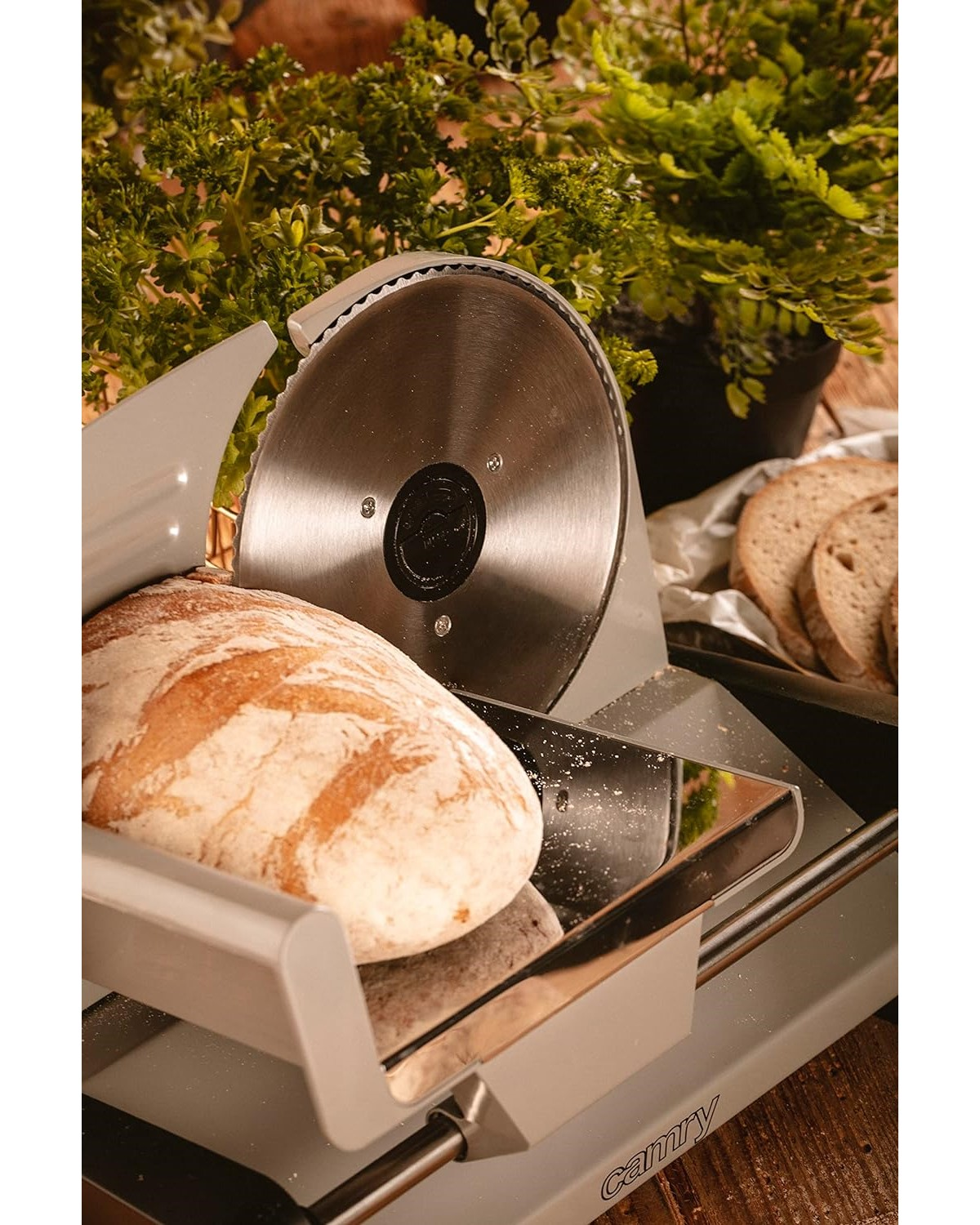 Brotschneider schneidet Brot, im Hintergrund Grünpflanzen.