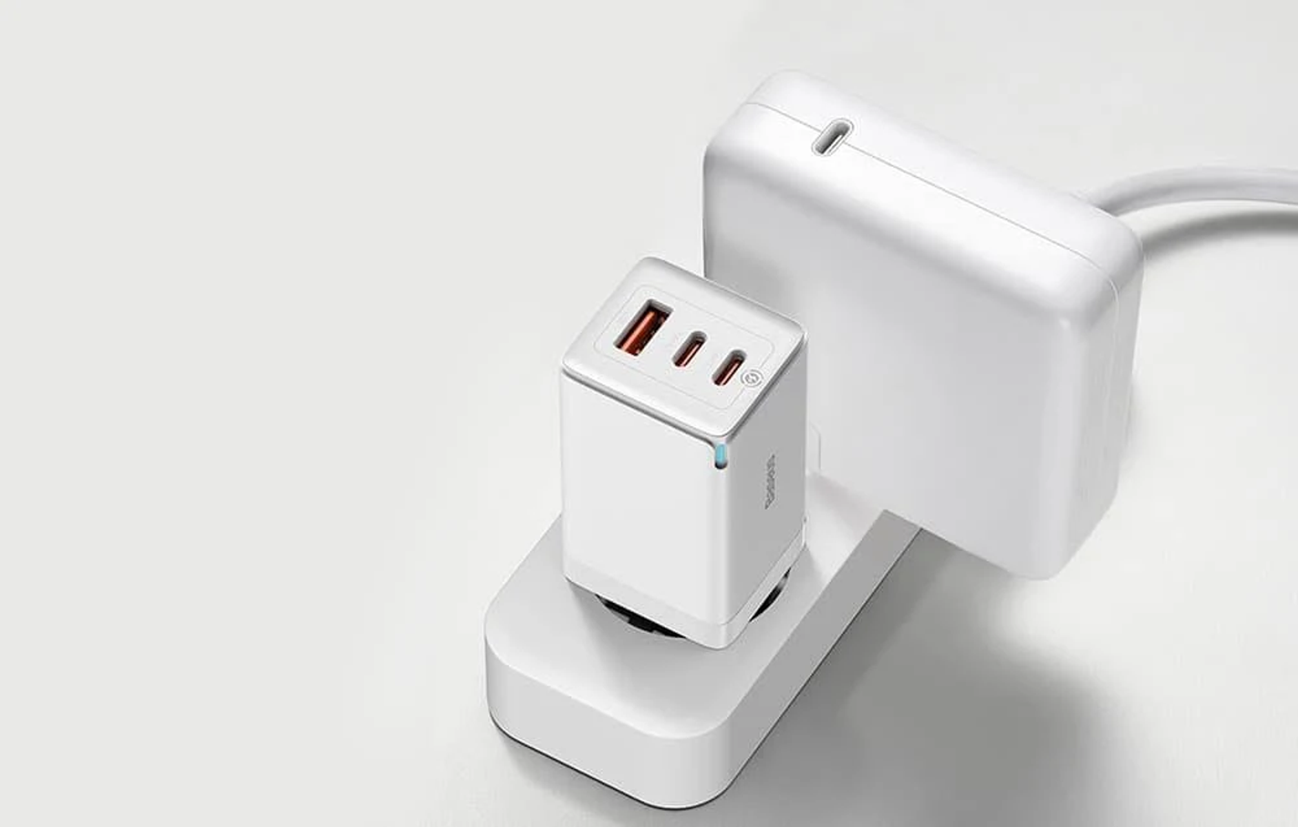 Biały zasilacz z trzema portami i białą wtyczką jest podłączony do białego gniazdka ściennego.