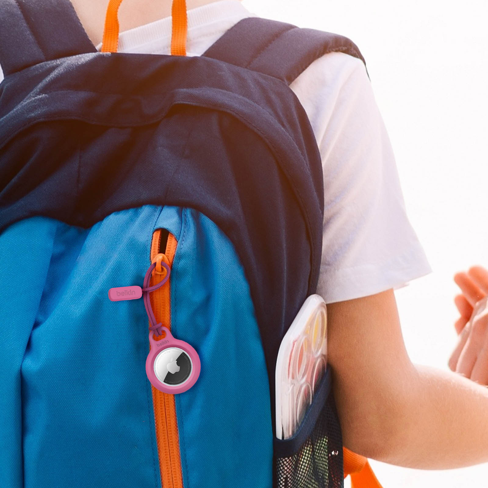 Plecak z dołączonym AirTagiem. Różowe etui AirTag. Białe tło.