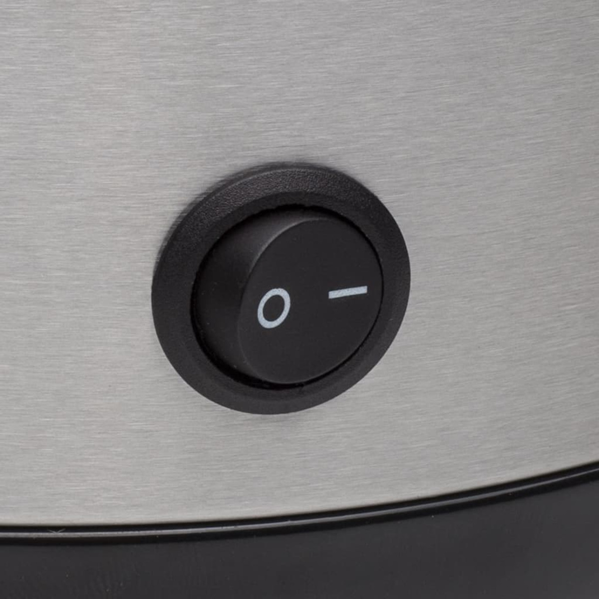 Un pulsante di accensione nero su un elettrodomestico argentato, primo piano, il pulsante ha una 'O' e una linea.