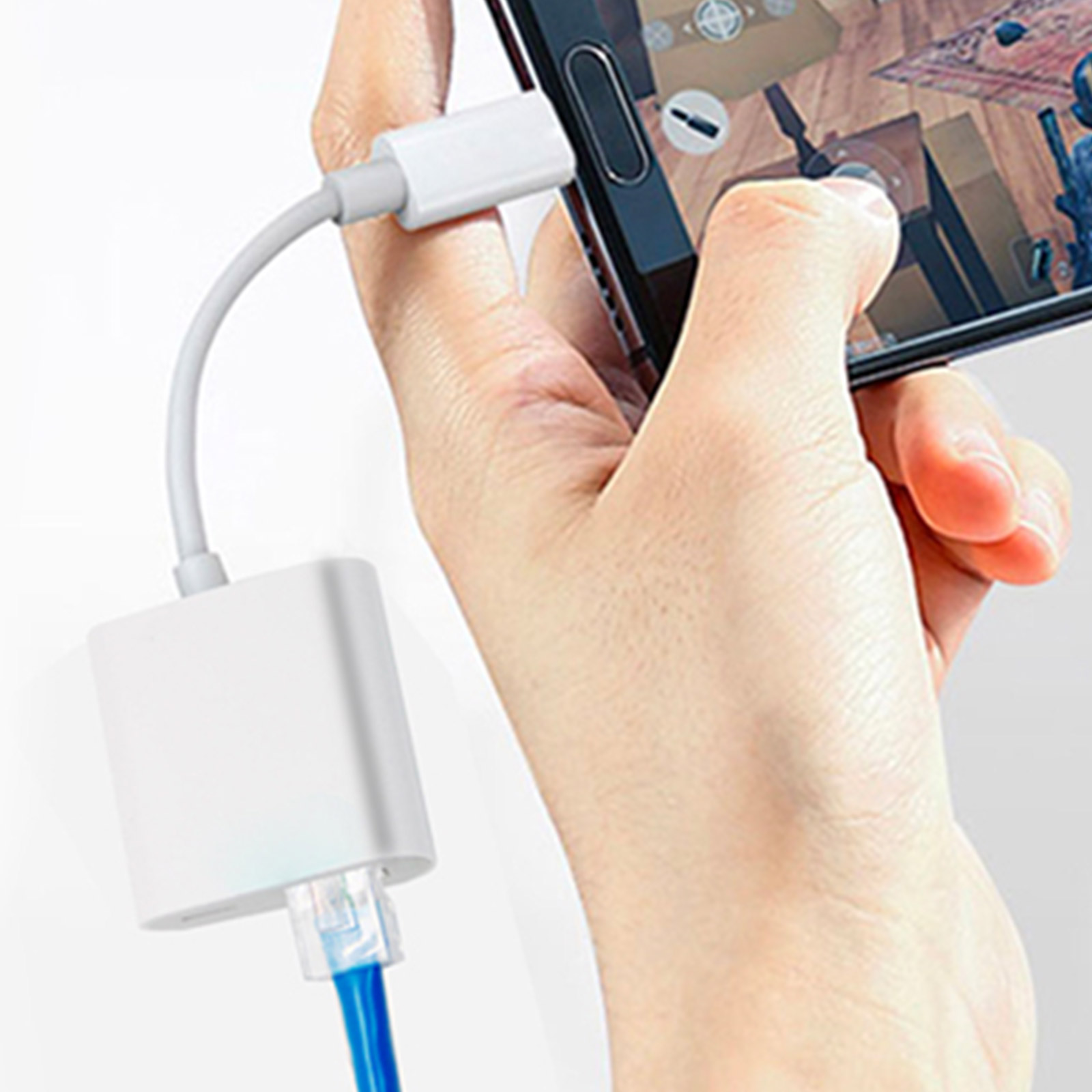 Una mano che tiene un telefono collegato a un adattatore bianco e un cavo di rete blu.