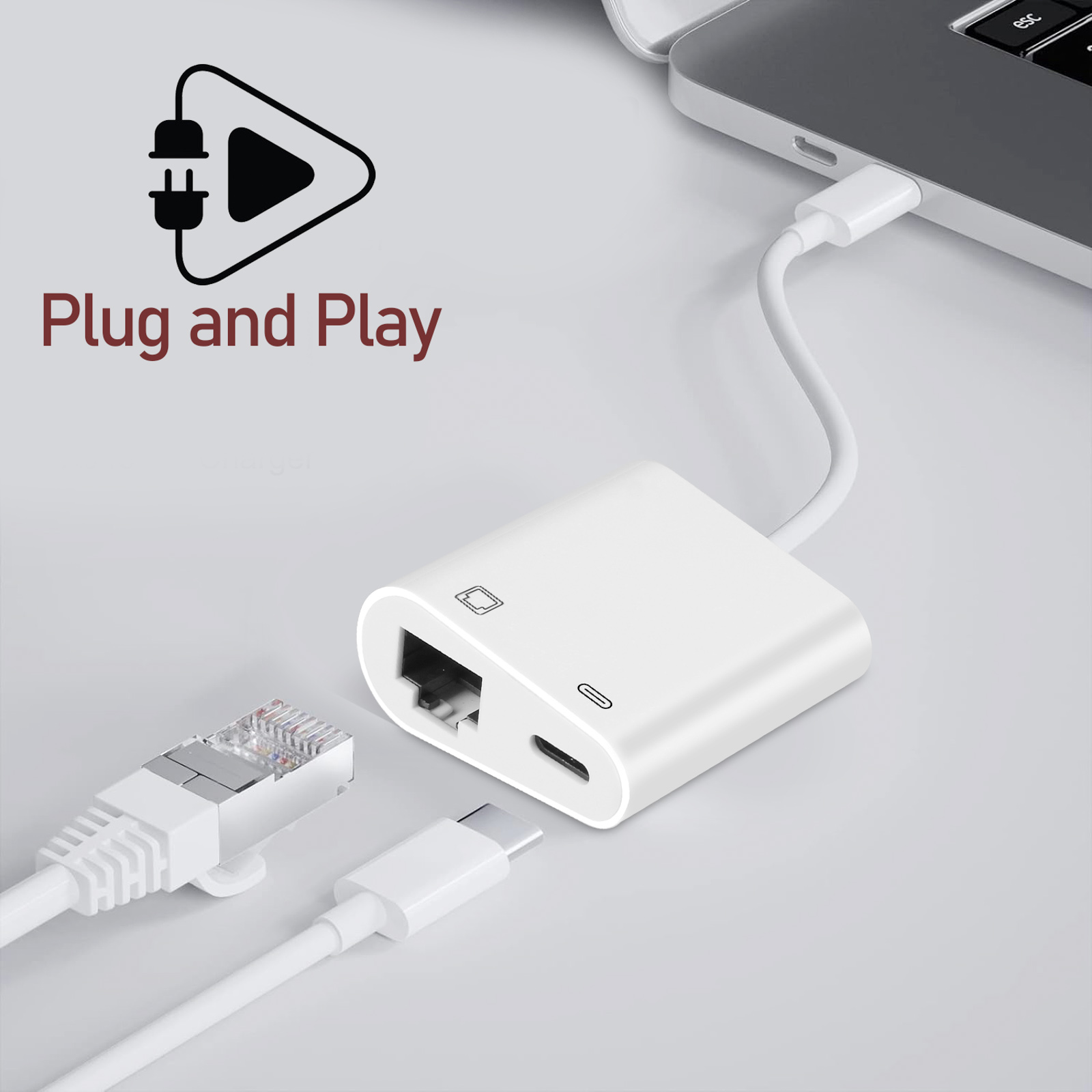 Un adattatore bianco con porte Ethernet e USB-C, collegato a cavi, etichettato 'Plug and Play'.