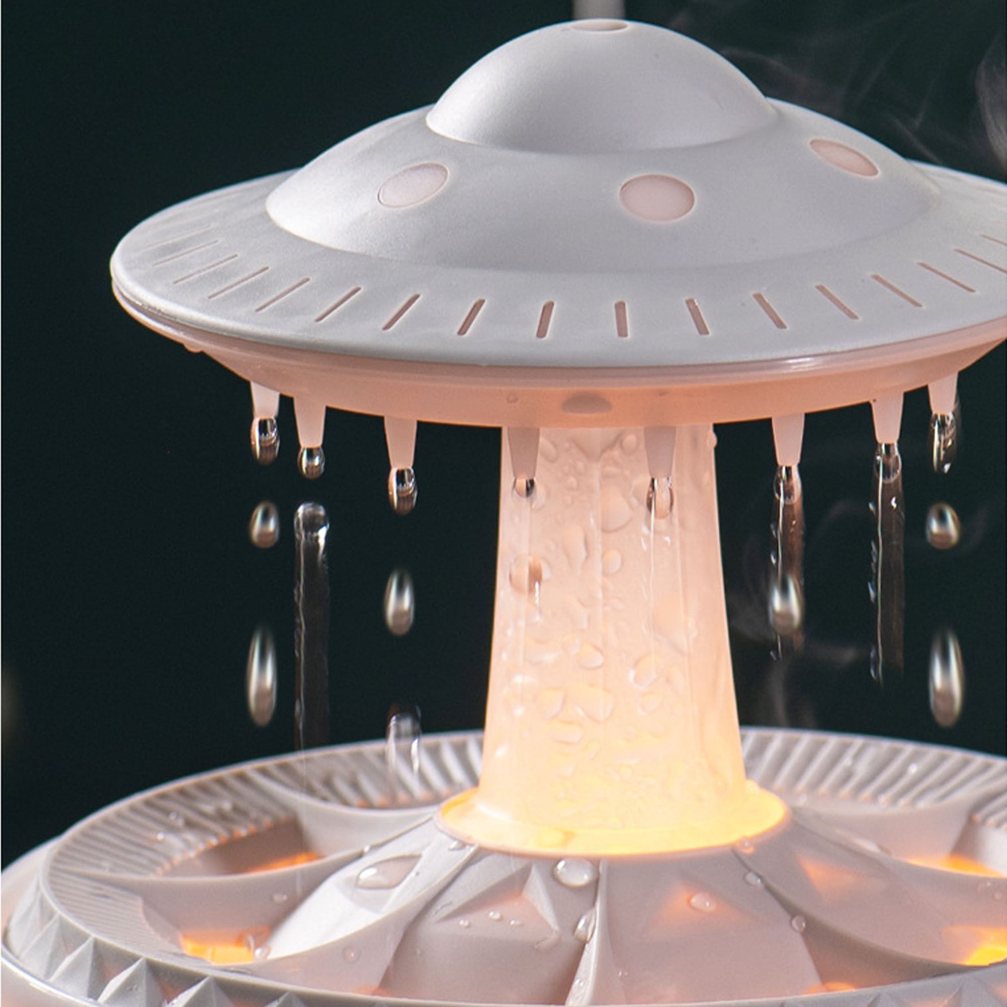 Ein weißer Luftbefeuchter in Form eines UFOs, mit fallenden Wassertropfen.